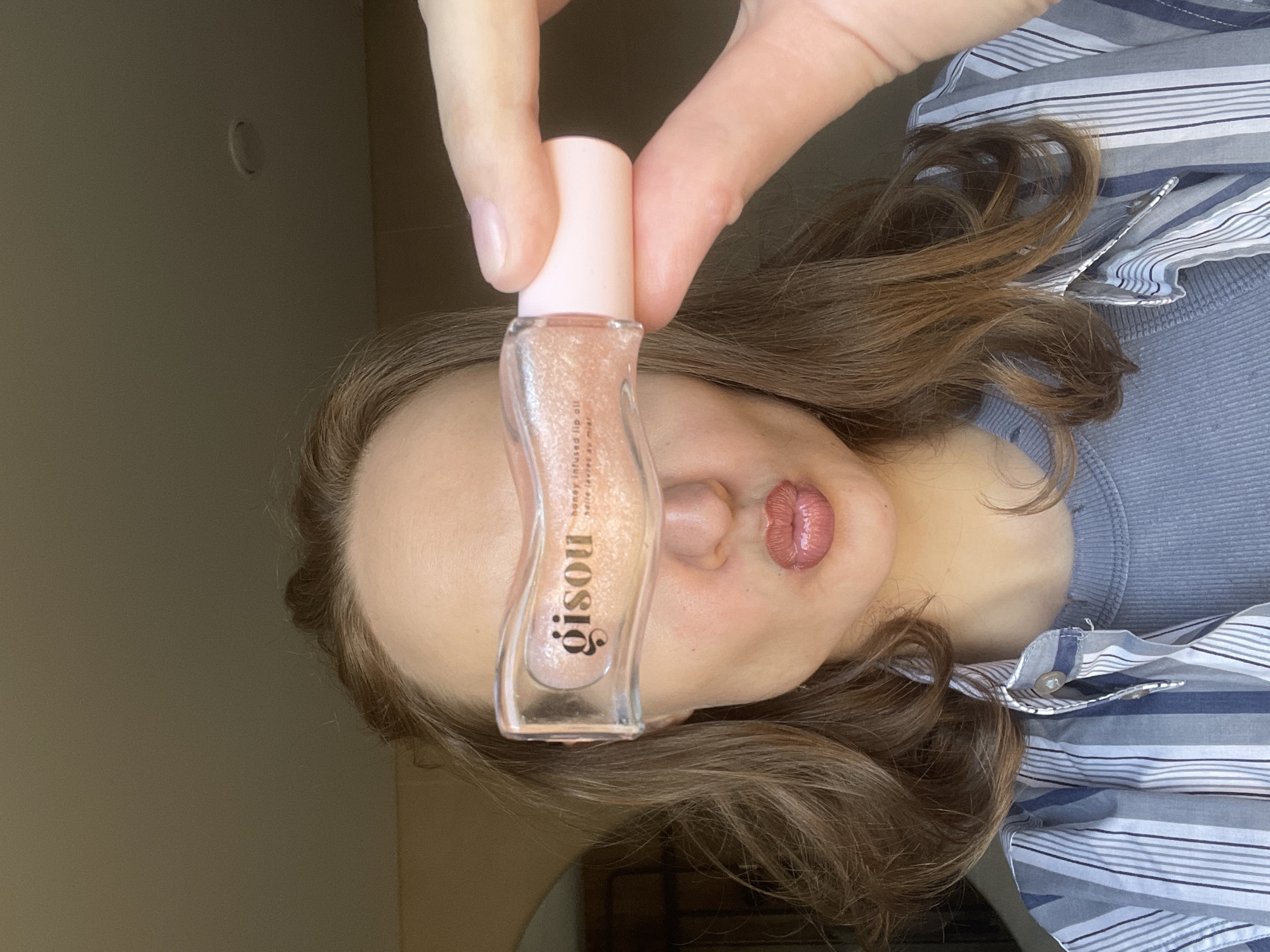 Woman displays Gisou lip oil product in Russian forest area