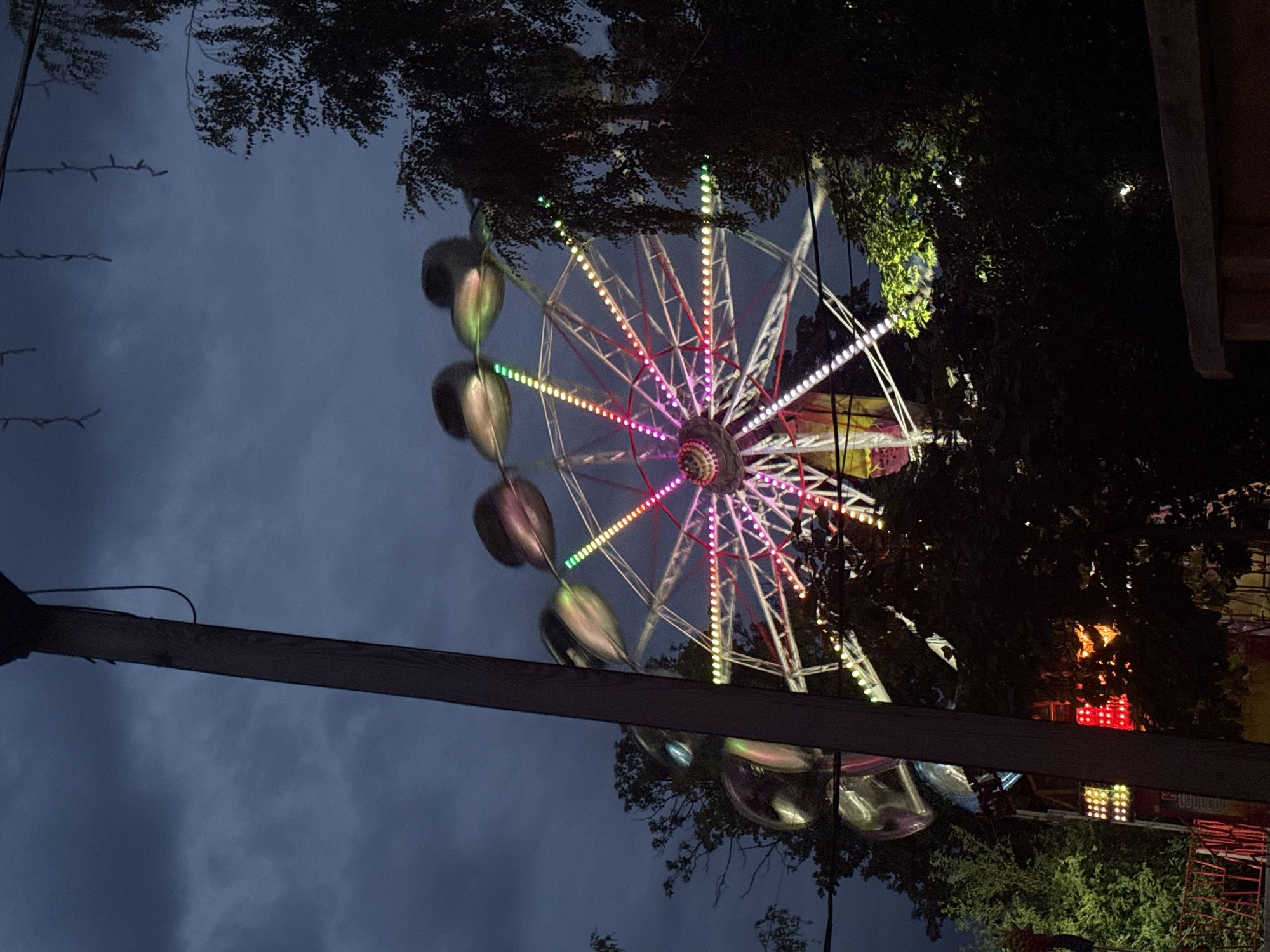 Colorful Ferris wheel lights up at dusk