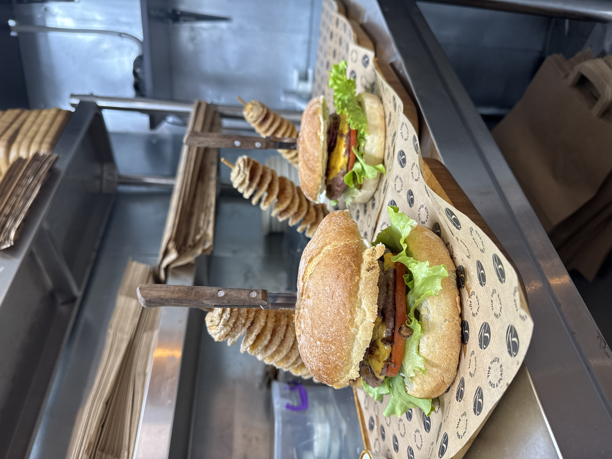 Food truck serves burgers and spiral potatoes on wooden trays