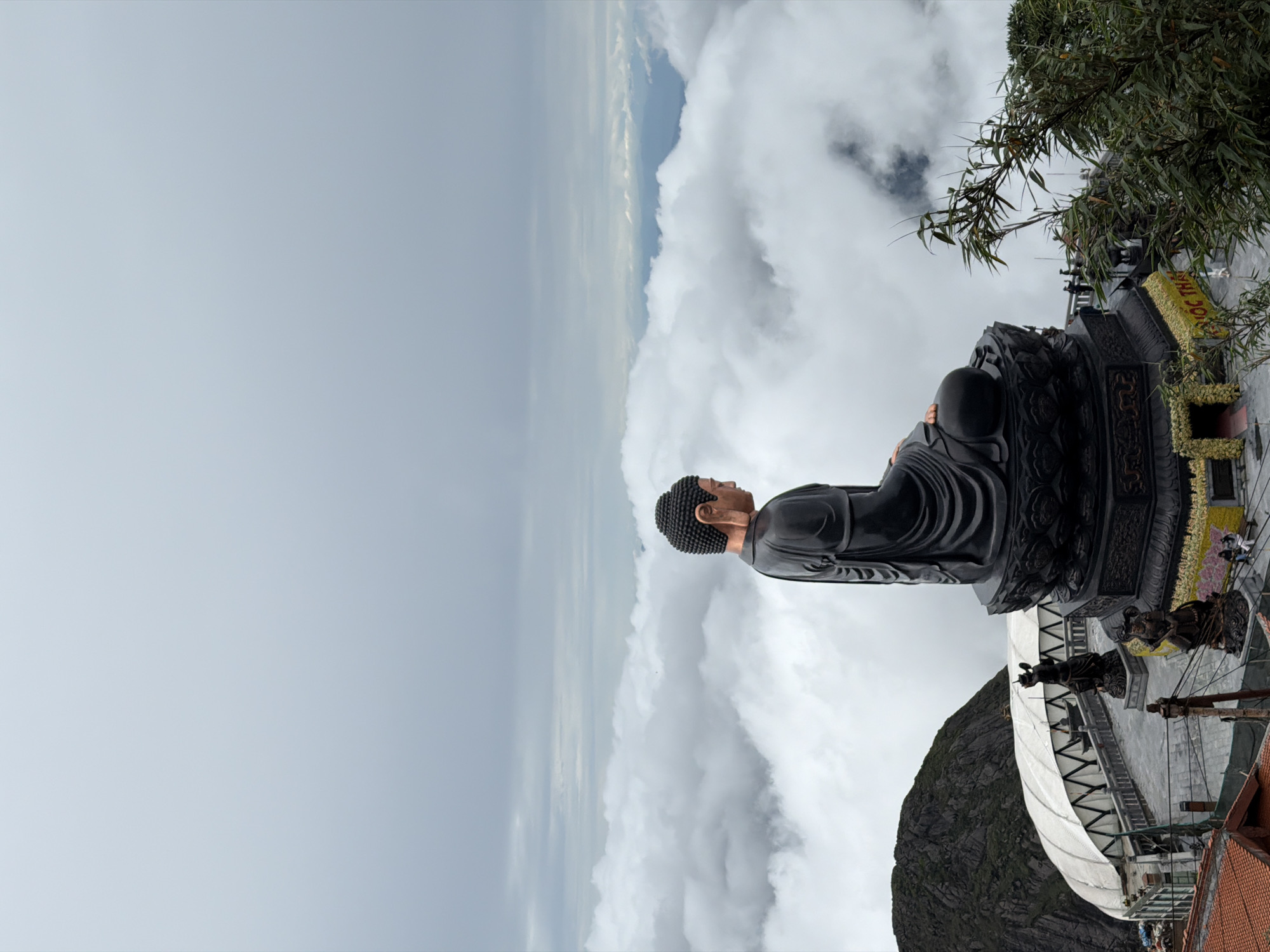 Buddha statue and mountain tower at a misty Vietnamese highland site