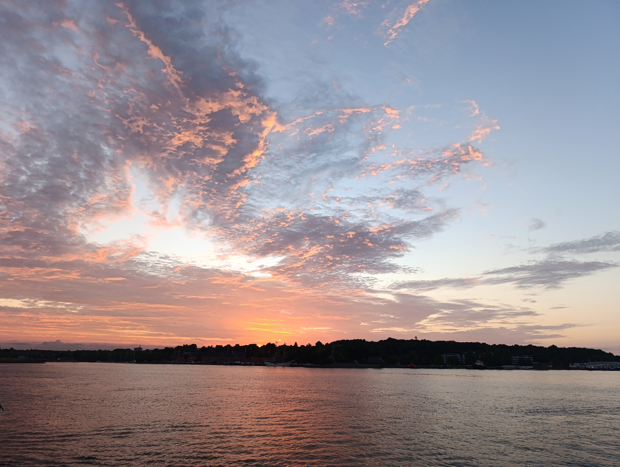 Sunset over Kiel Fjord with a silhouetted city skyline