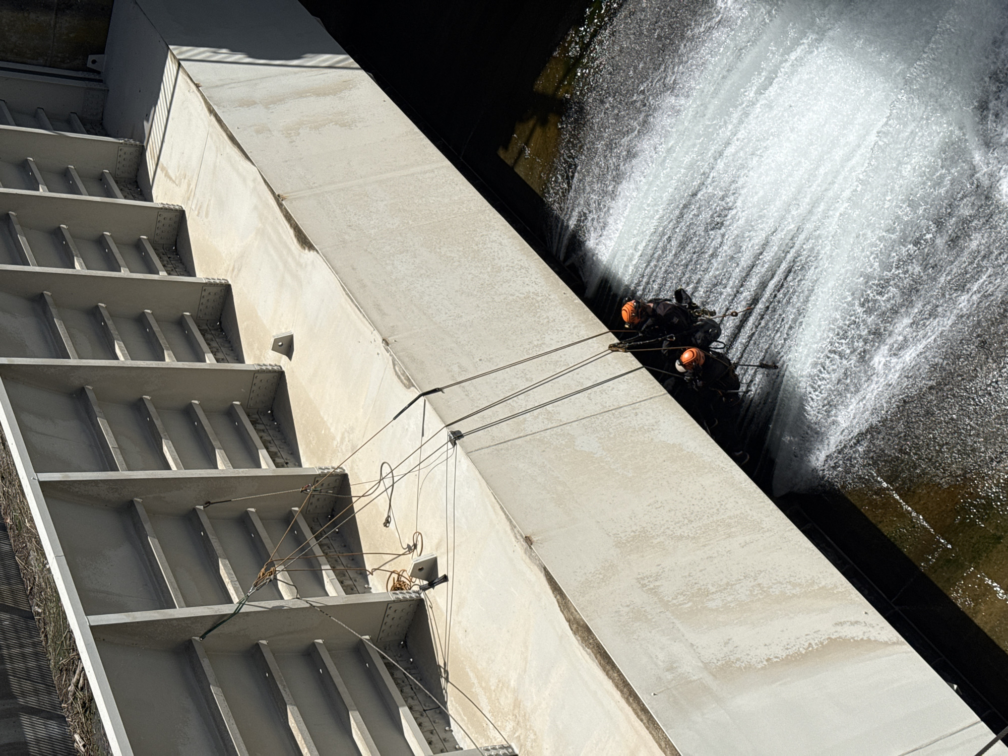 Two helmeted people suspended near dam structure in La Saulce
