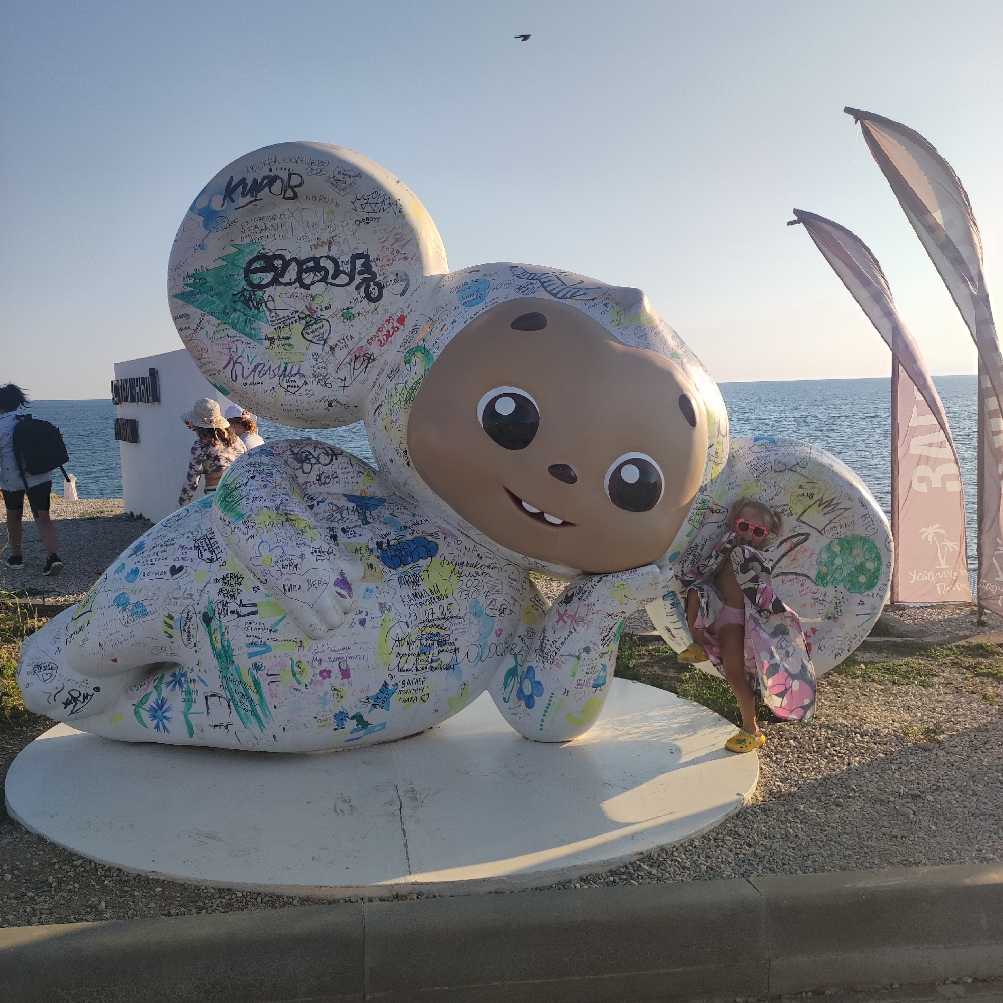Cheburashka statue and vintage cars at a seaside stop