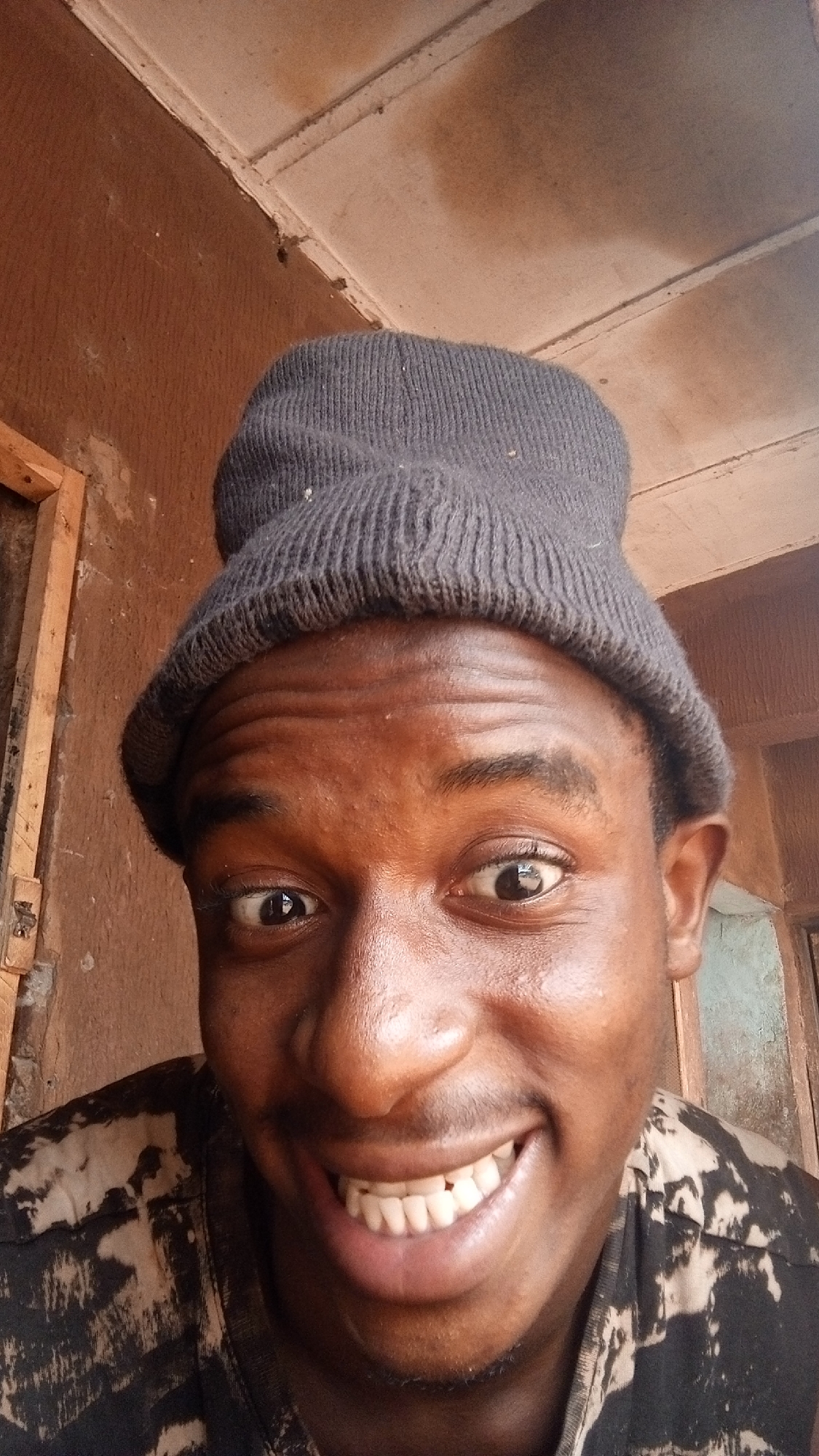 Young man in beanie photographed smiling indoors
