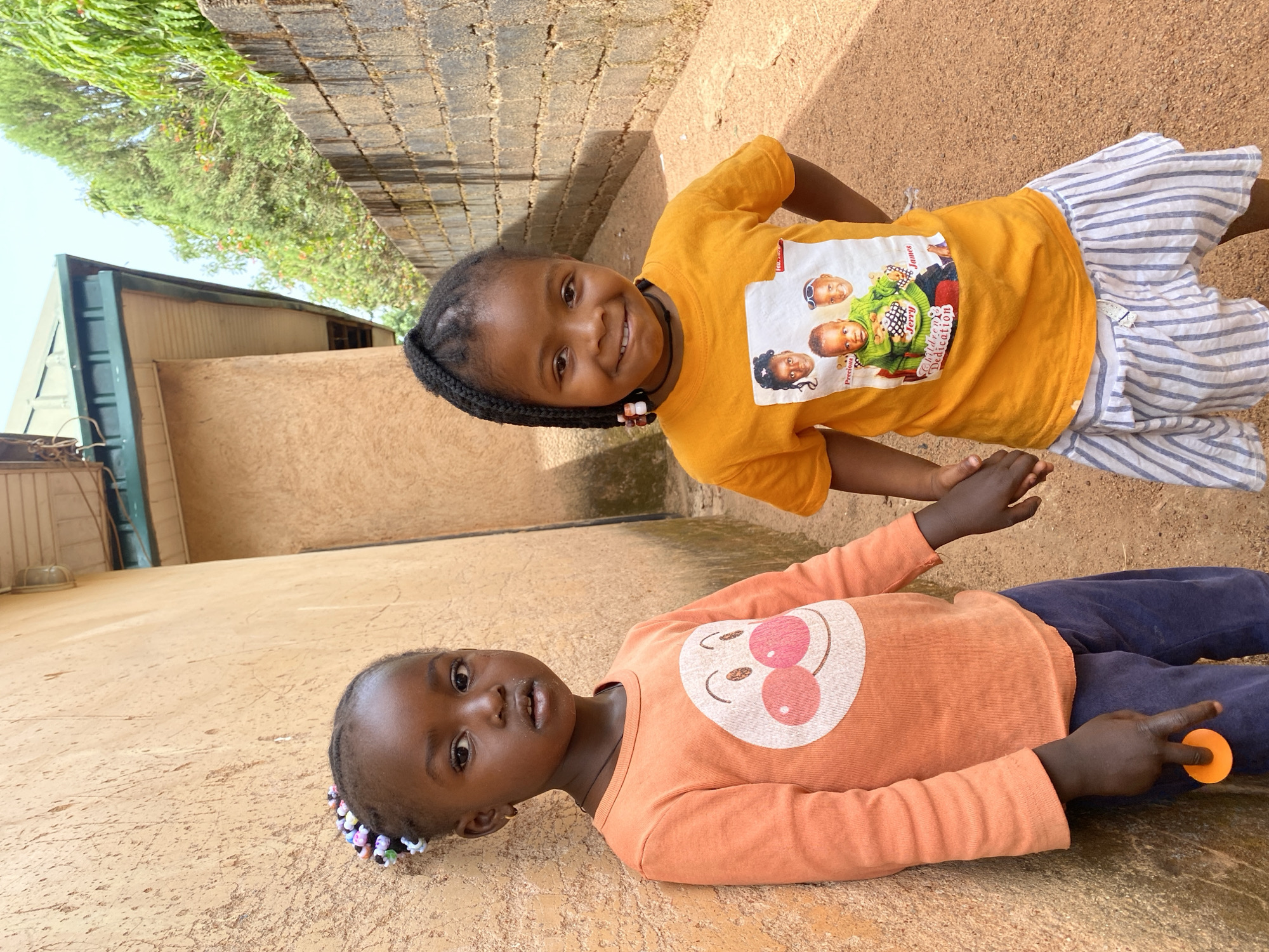 Two girls share fruit during morning play in Kuru, Nigeria