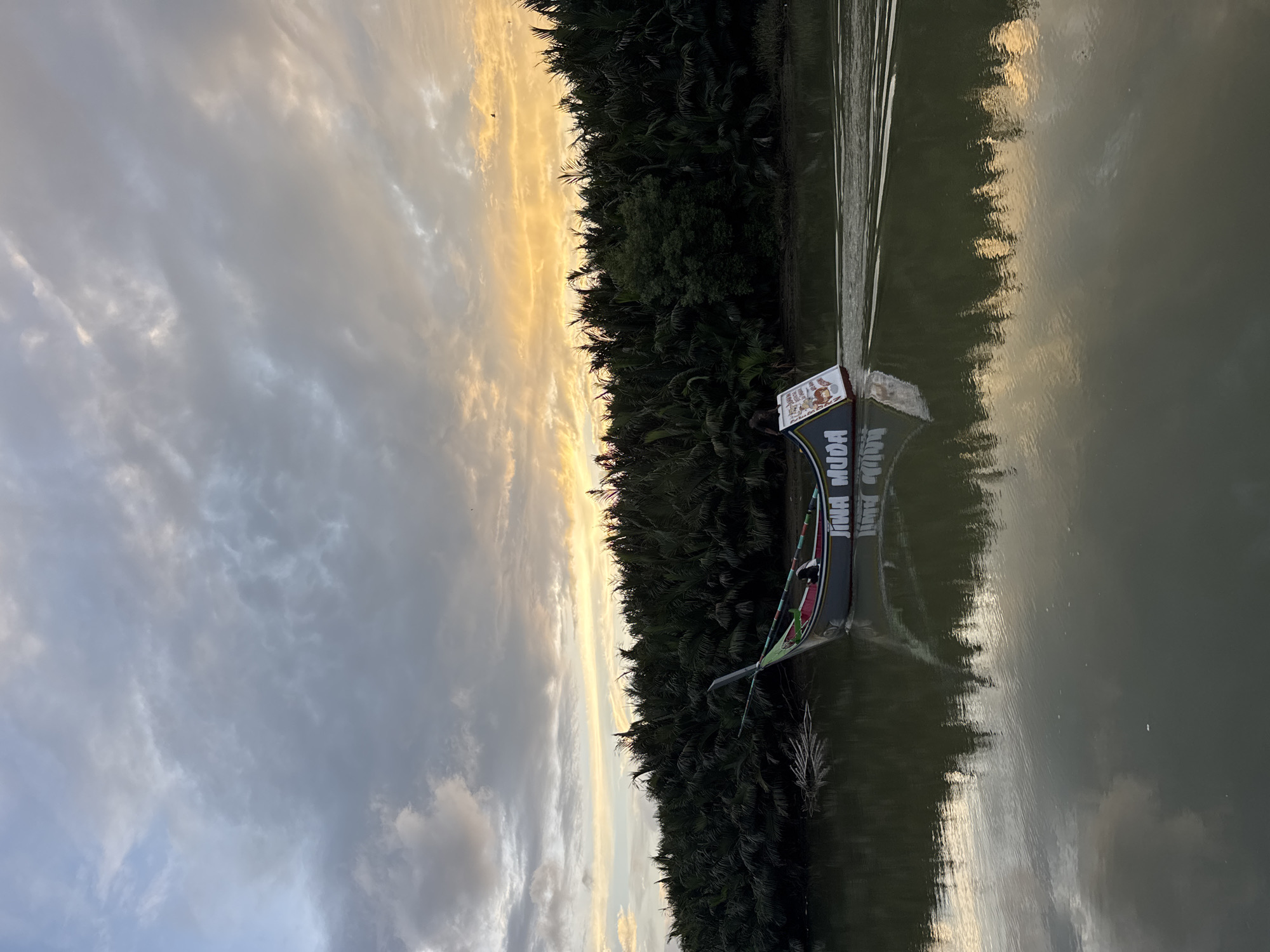 Boat 'JIWA MUDA' glides down a calm river at sunset