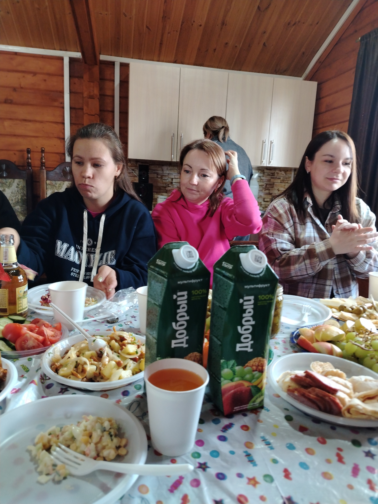 Women share meal in wooden cabin setting