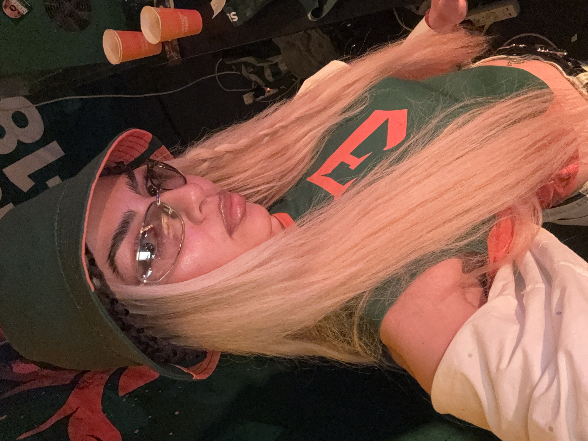 Green bucket hat and clear glasses in a dim indoor setting