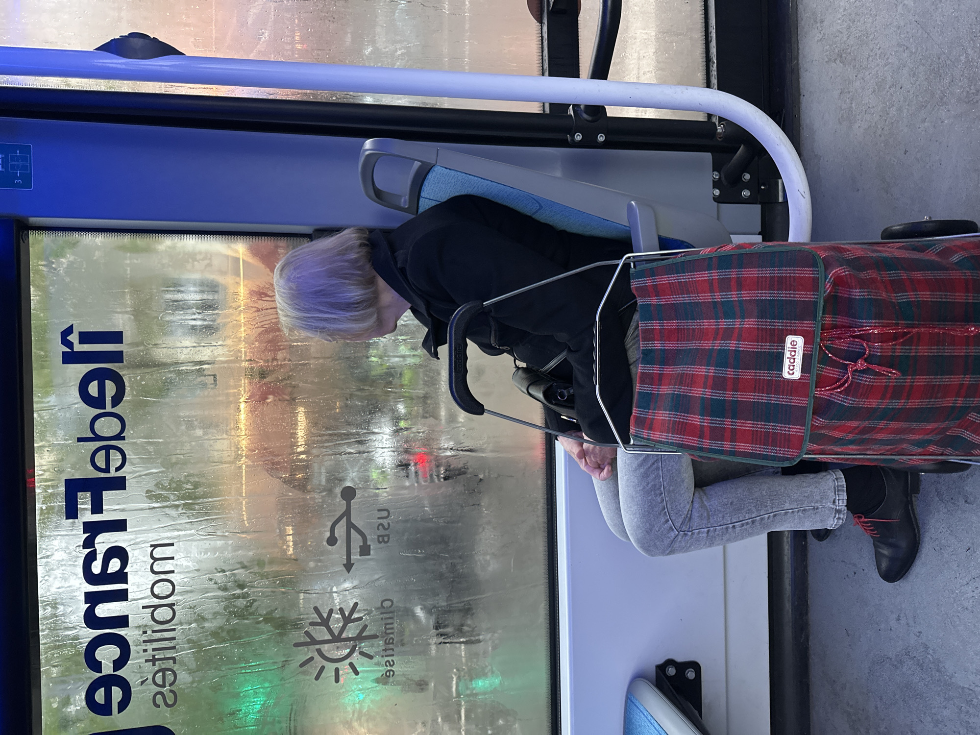 Elderly passenger rides Paris bus during rainy afternoon