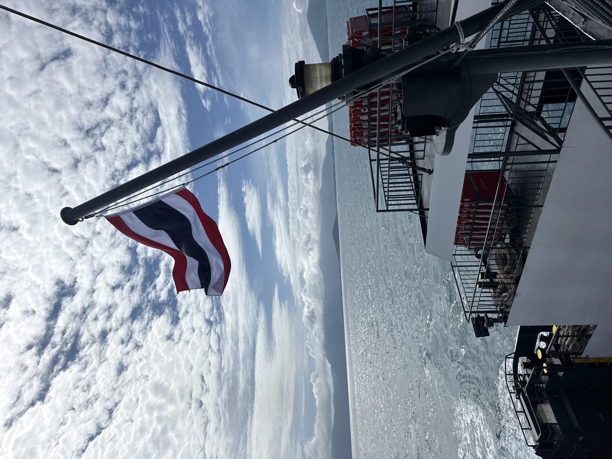 Thai flag flies from a ferry deck under open skies