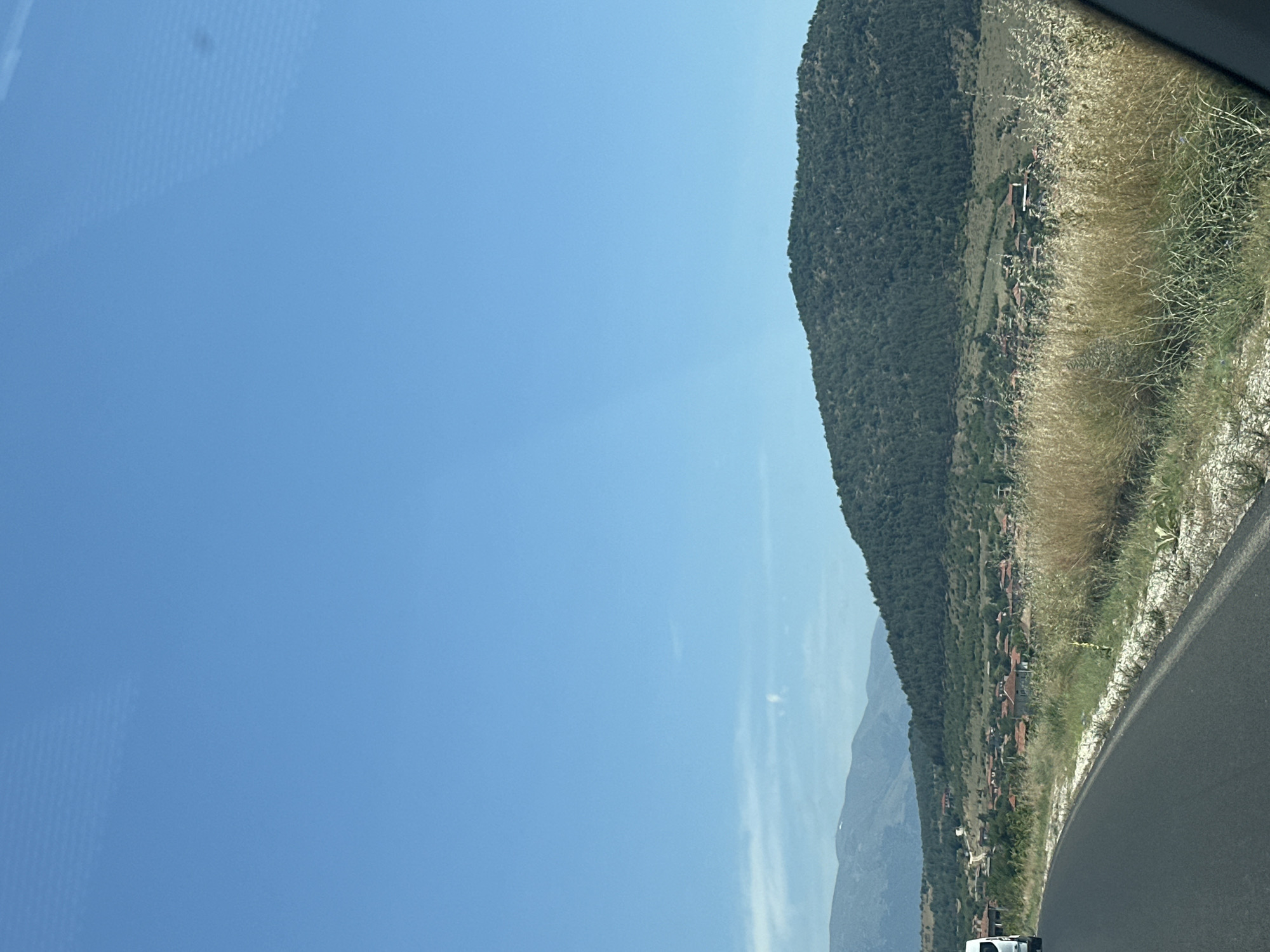 Quiet rural road curves through dry summer landscape in Bulgaria