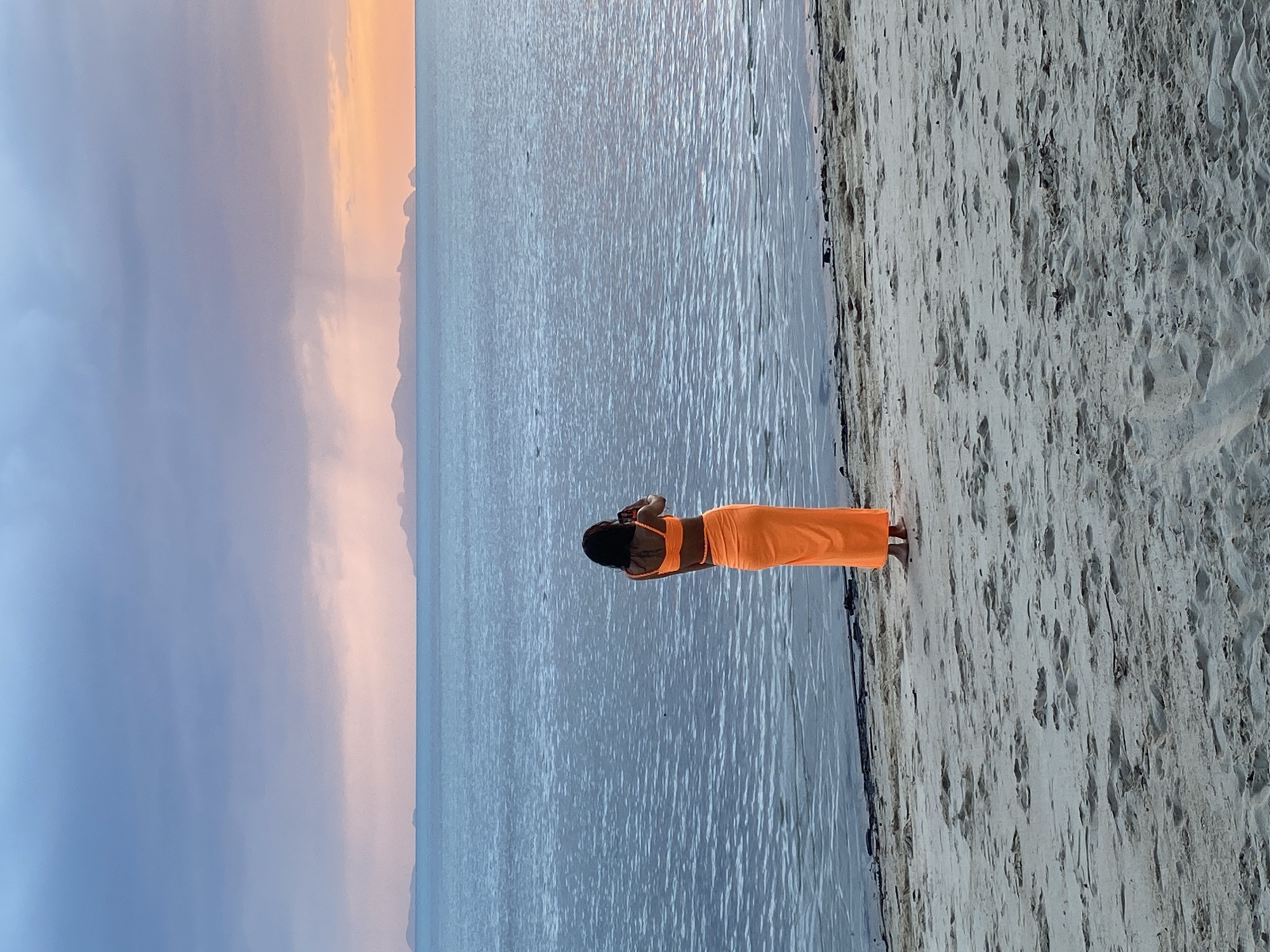 Orange outfit, Ko Samui beach, phone out at the water's edge