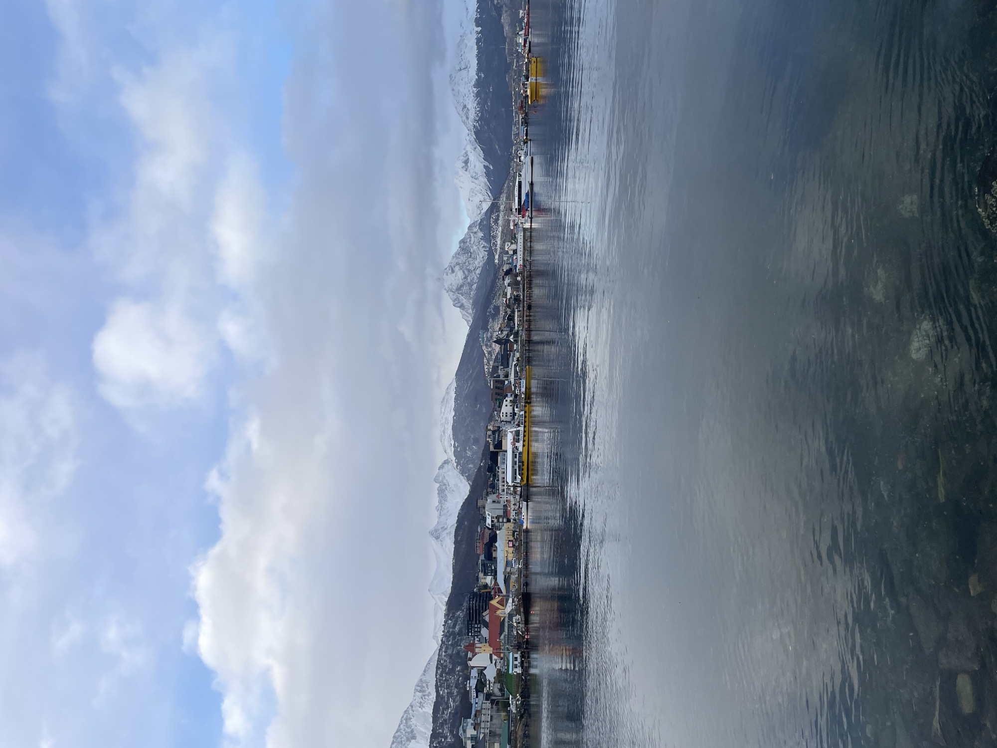 Tourists explore Ushuaia waterfront and memorials under overcast skies