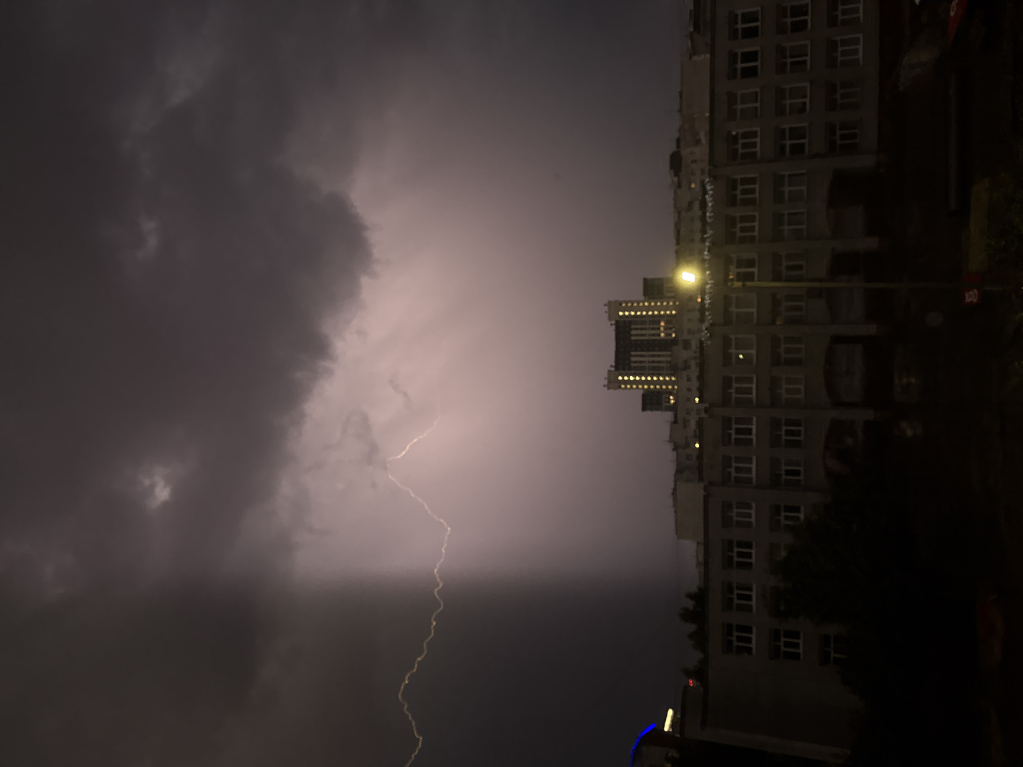 Thunderstorm with lightning strikes over city buildings