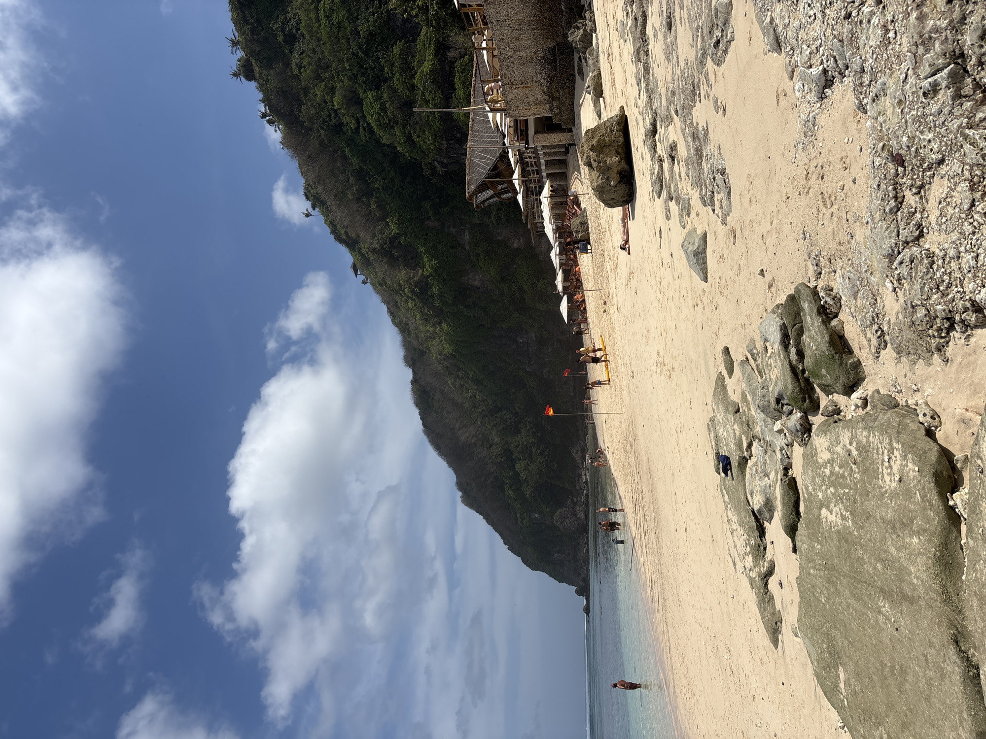 Quiet Kuta Selatan beach, shells on sand, hills behind