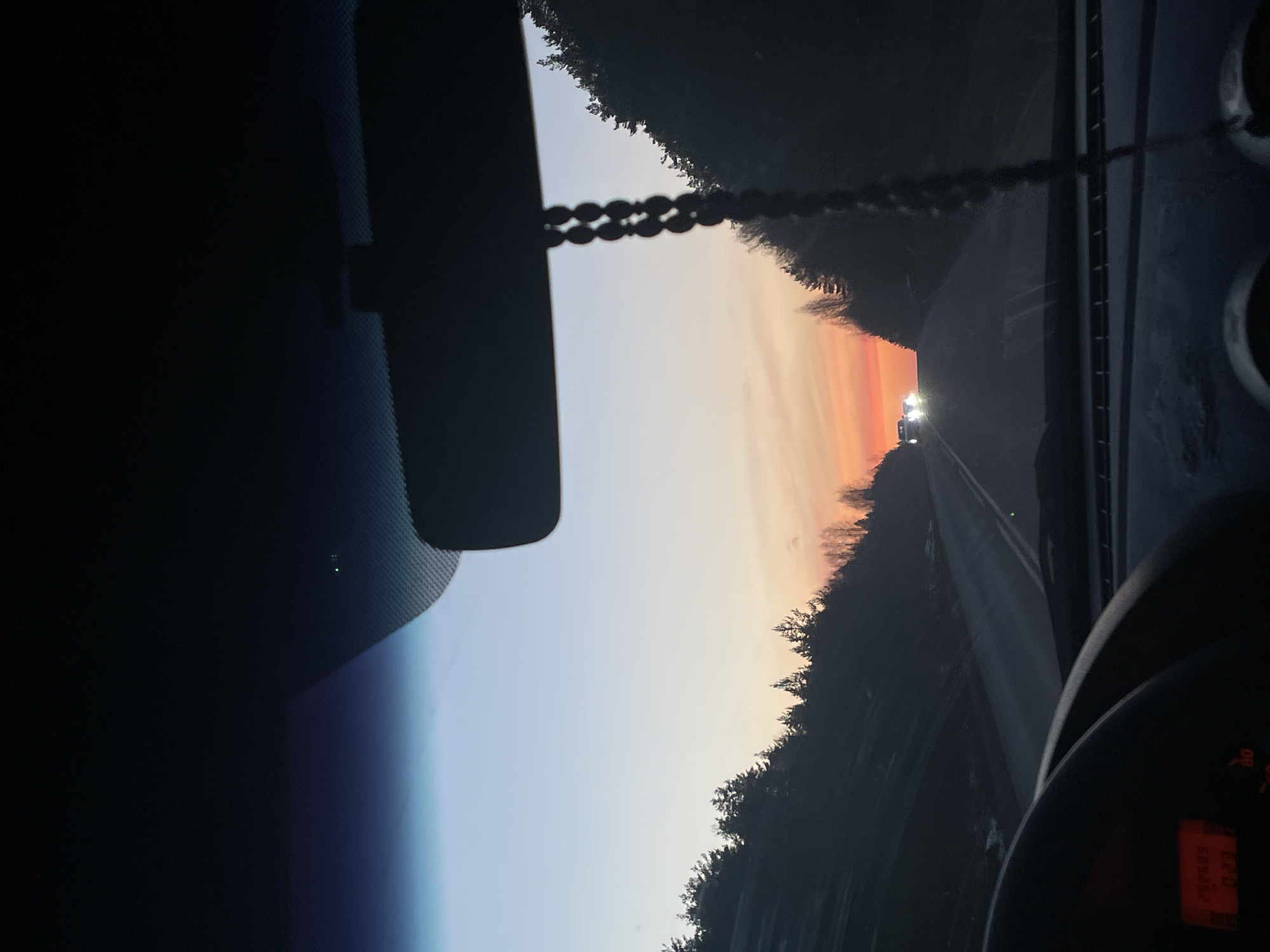 Driver captures sunset view during rural road journey