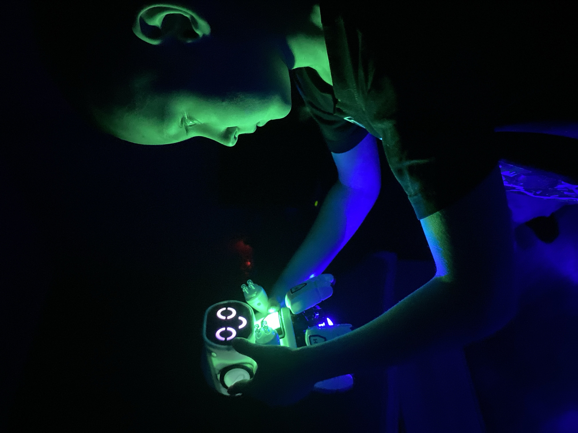 Child plays with glowing RC cars in dimly lit room