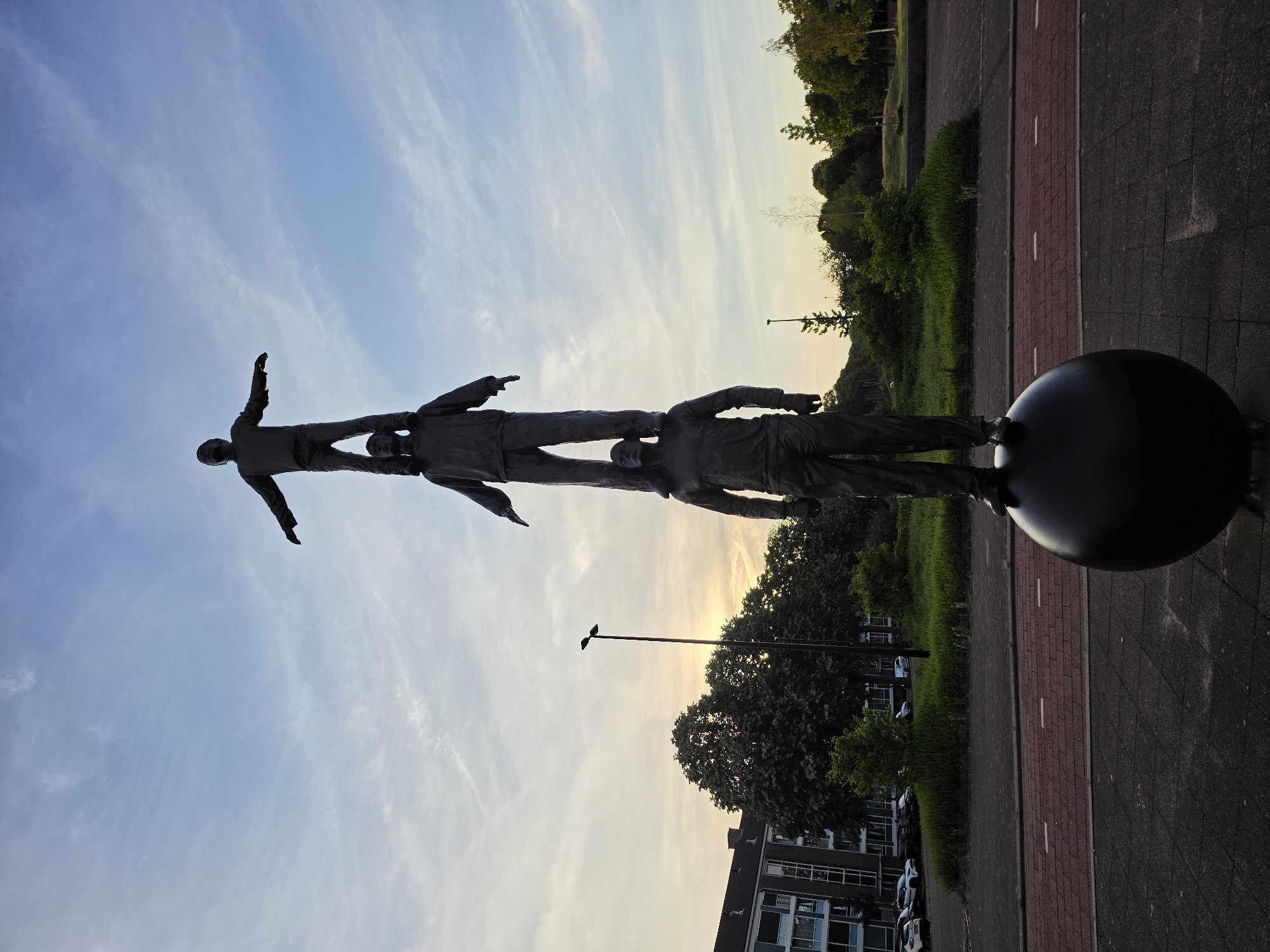 Stacked bronze figures rise in Rijswijk at dusk
