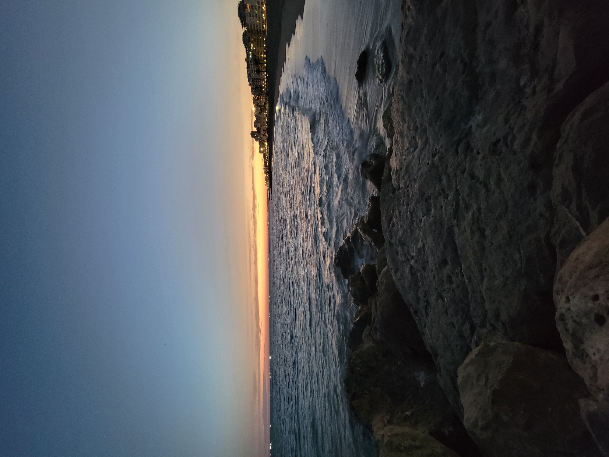 Dusk settles over Quarteira's rocky Atlantic coastline