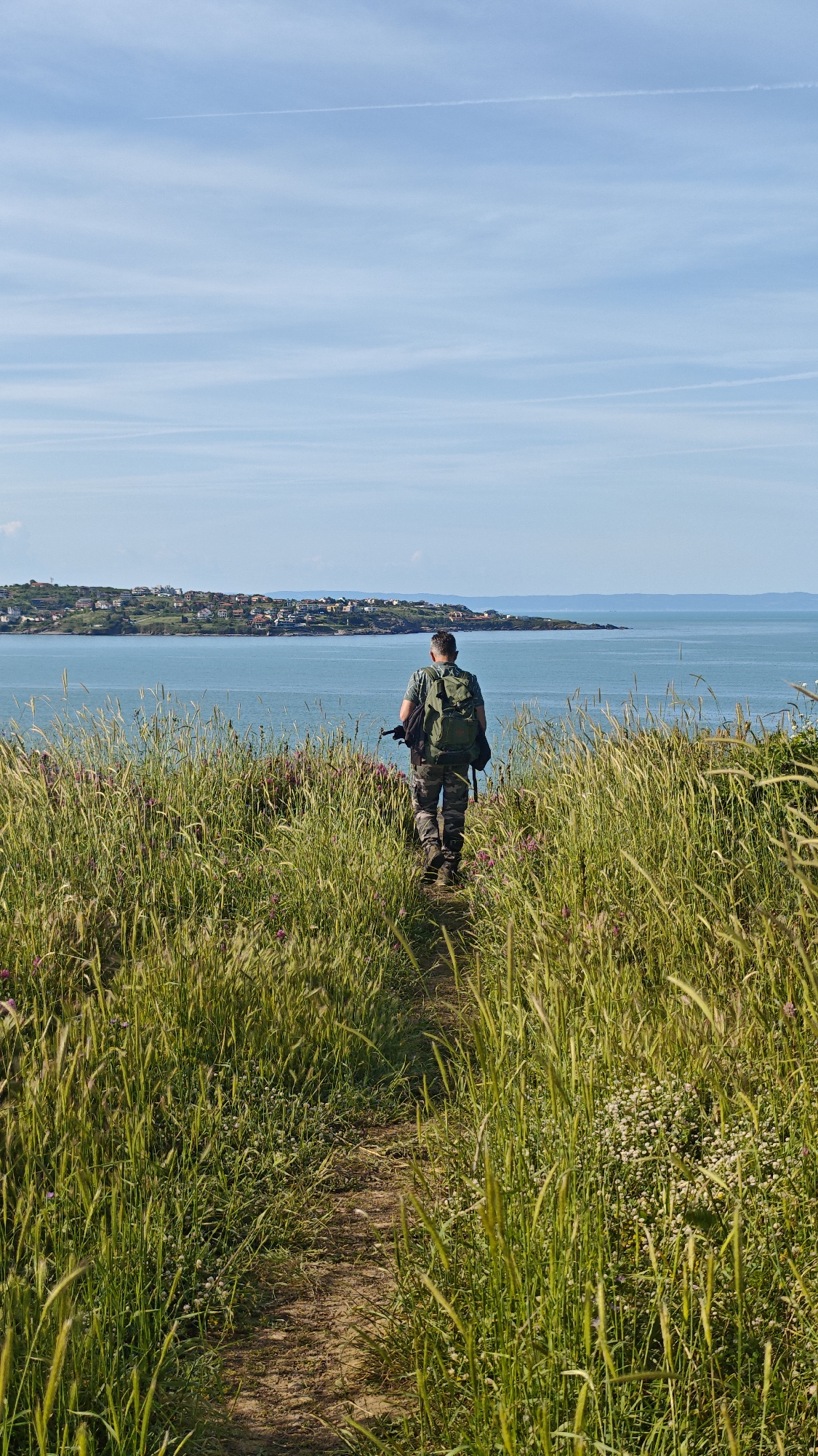 Man walks coastal path through wildflowers near Sozopol, Bulgaria