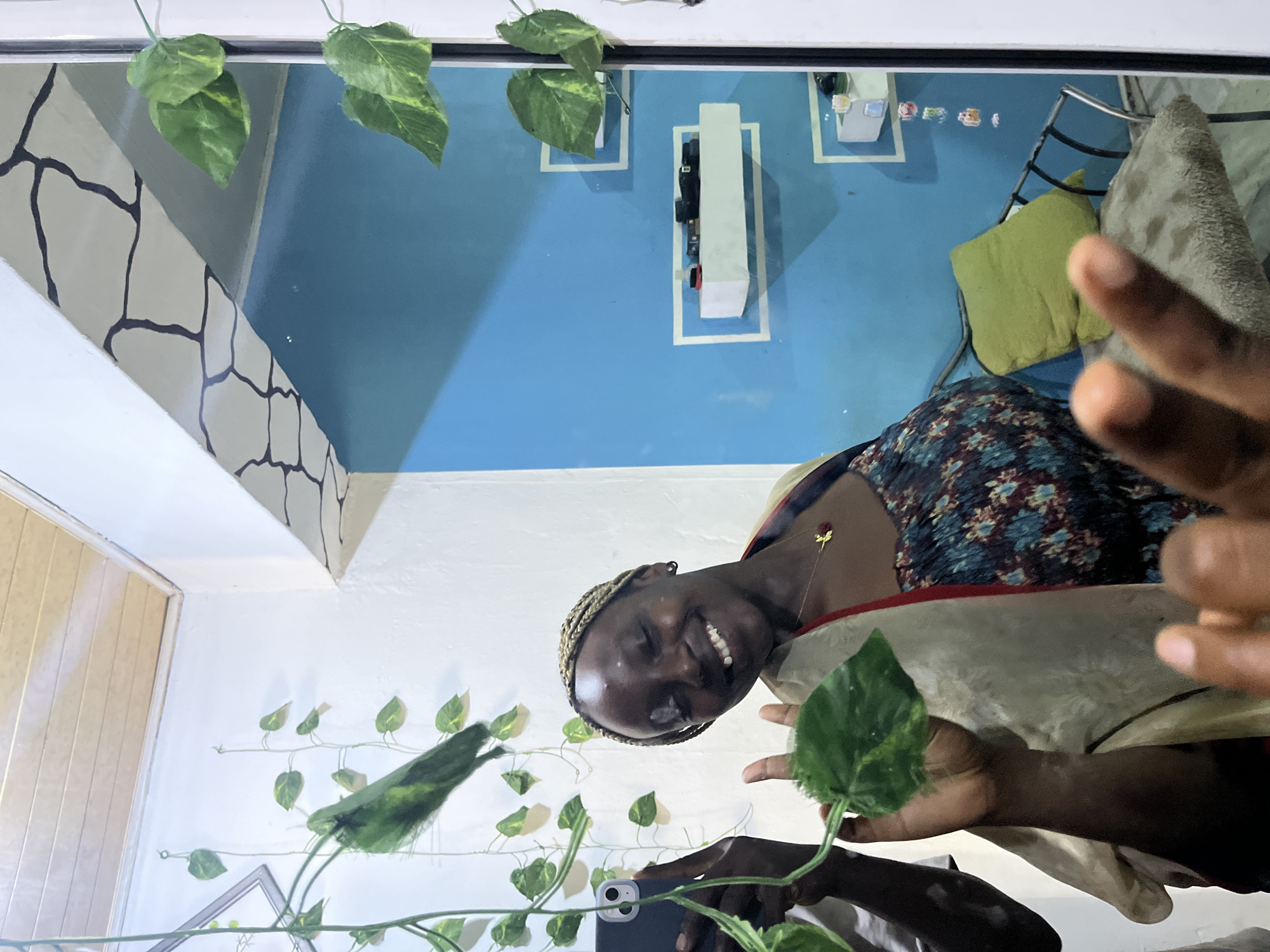 Person takes selfie, makes peace sign in plant-decorated room