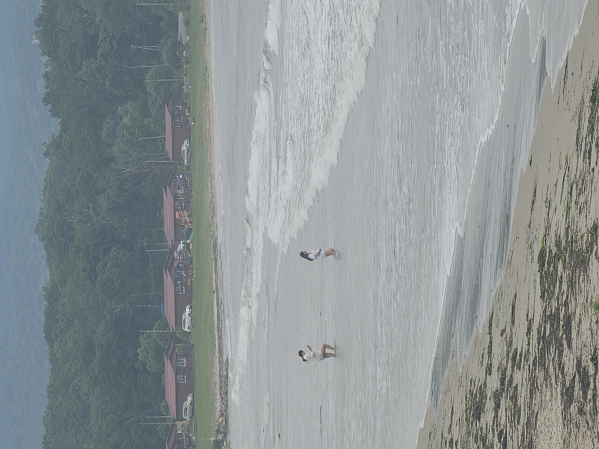 Wading in calm grey water on a cloudy Fokino beach