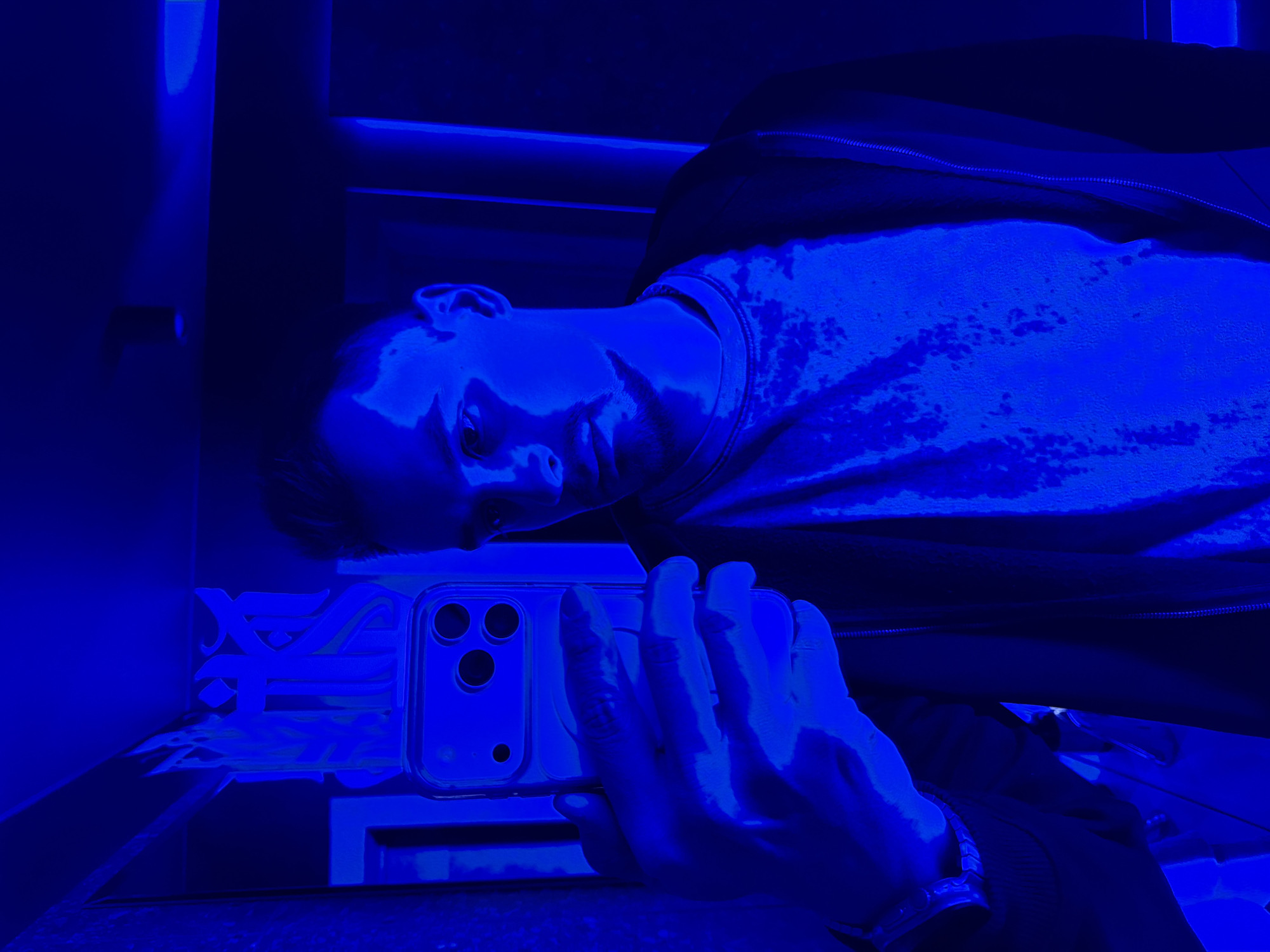 Man photographs with smartphone in dimly lit indoor setting