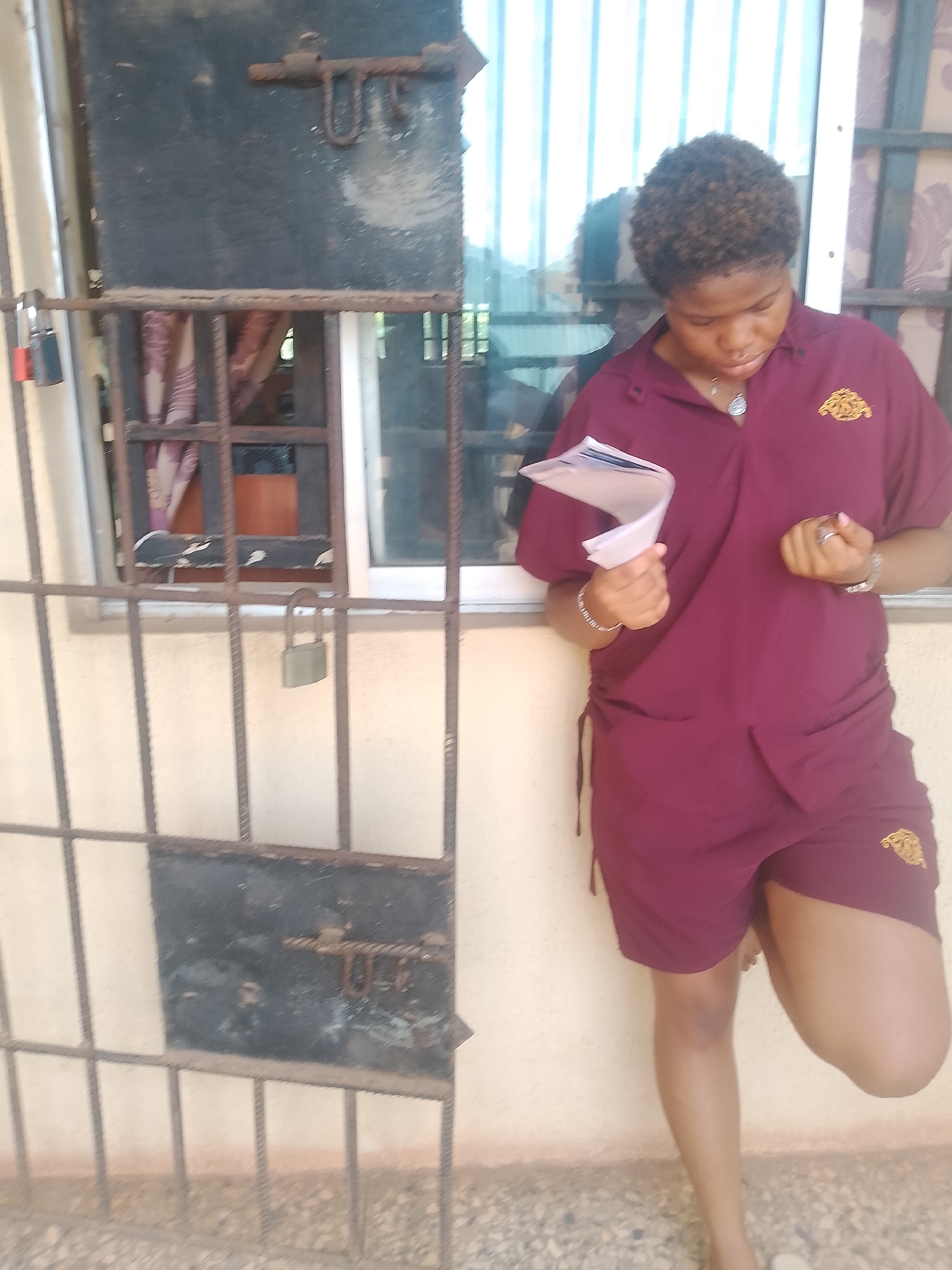Woman reads papers by barred window