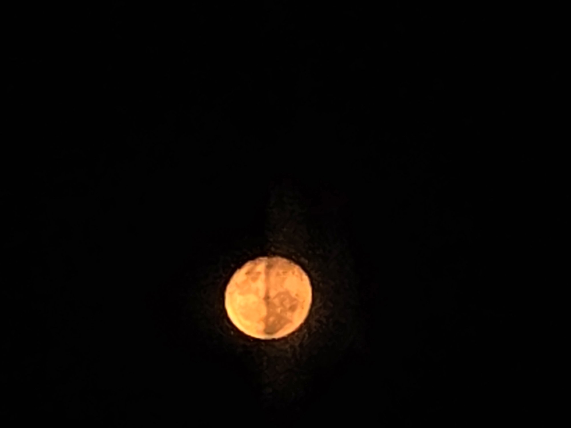 Full moon rising over Verona, orange and cloud-streaked