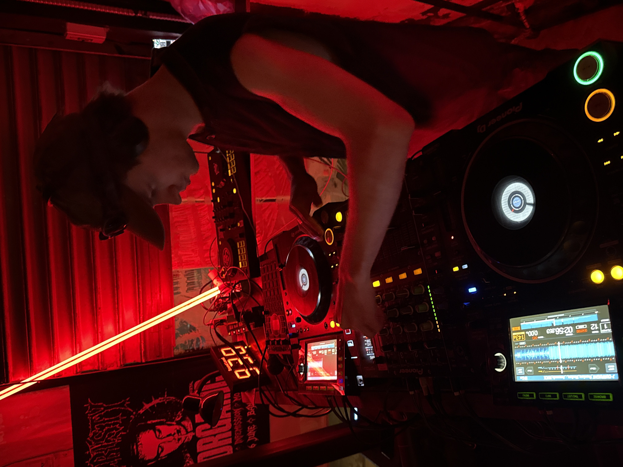 DJ set underway at a Bangkok club, red lights and full booth