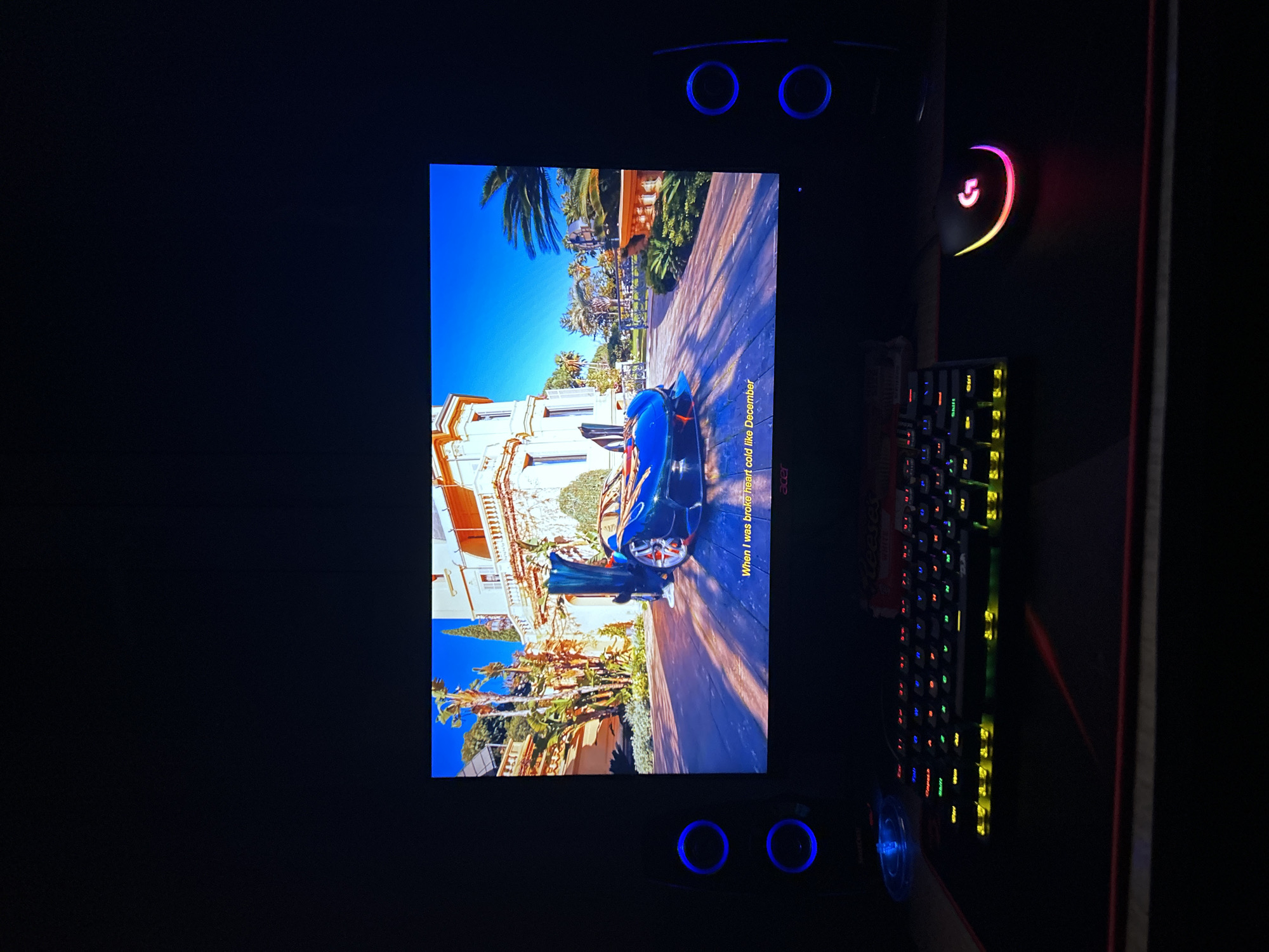 Computer monitor displays blue car scene in dark room