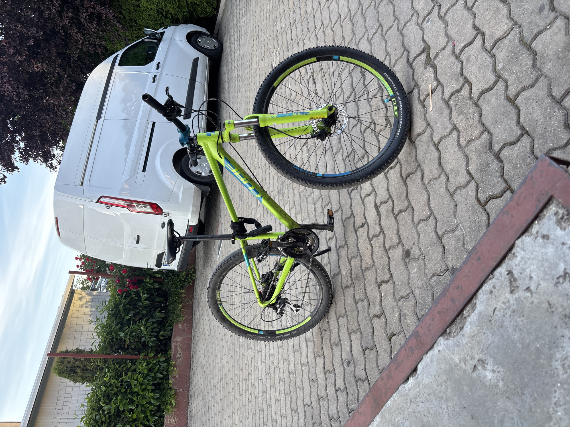 Mountain bike parked beside white van near rose bush