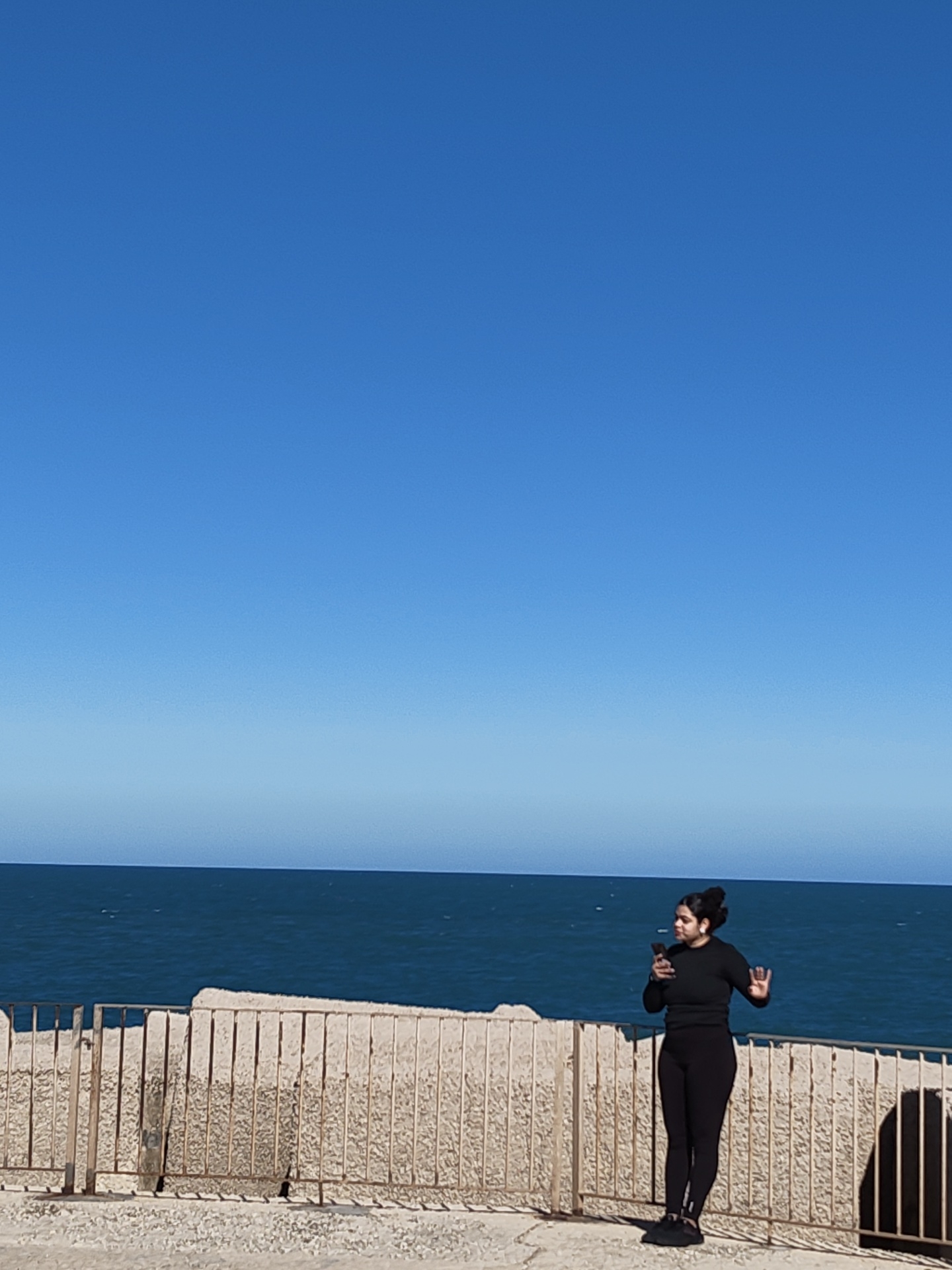 Tourists visit Dénia lighthouse pier on clear afternoon