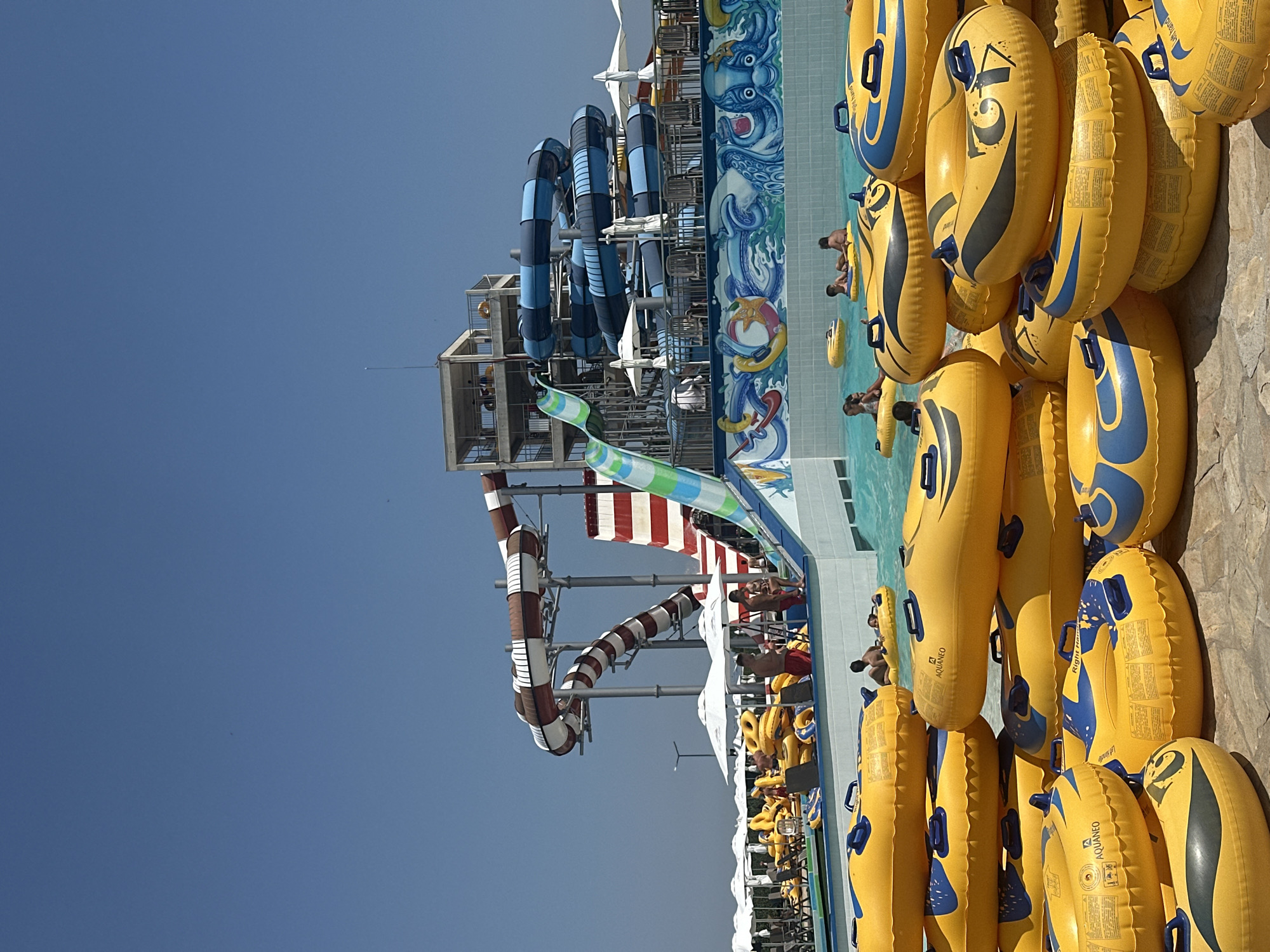 Sunny day at a water park, slides and a striking mural