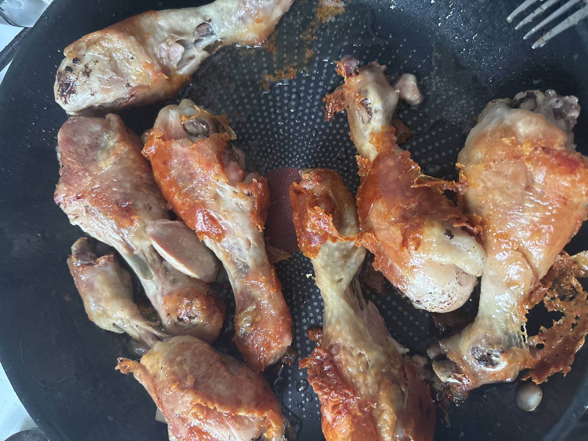 Crispy spiced chicken drumsticks frying in a pan