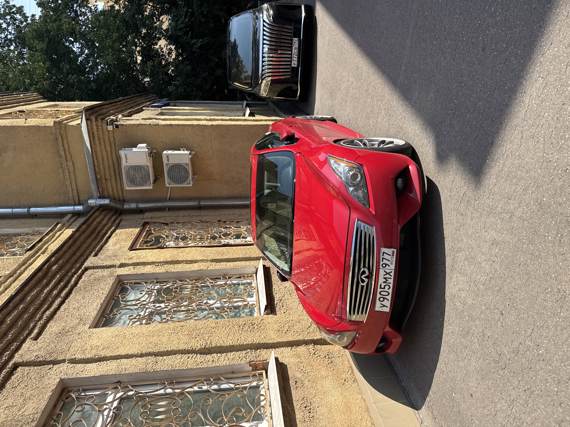 Red coupe and white Miata parked near ornate Moscow building