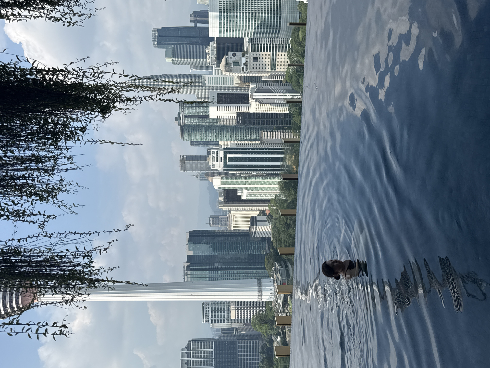 Woman enjoys rooftop infinity pool overlooking Kuala Lumpur skyline