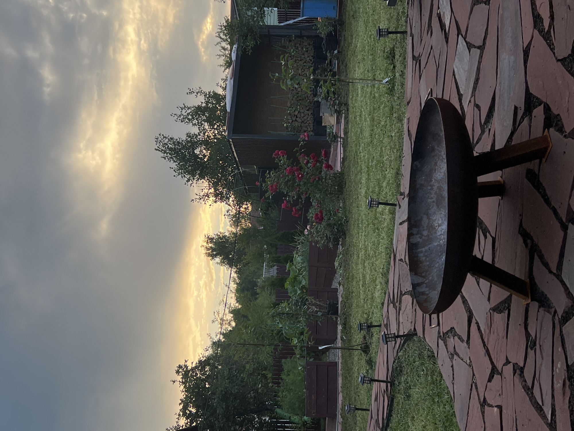 Dusk settles over a rustic backyard with a fire pit in Luch