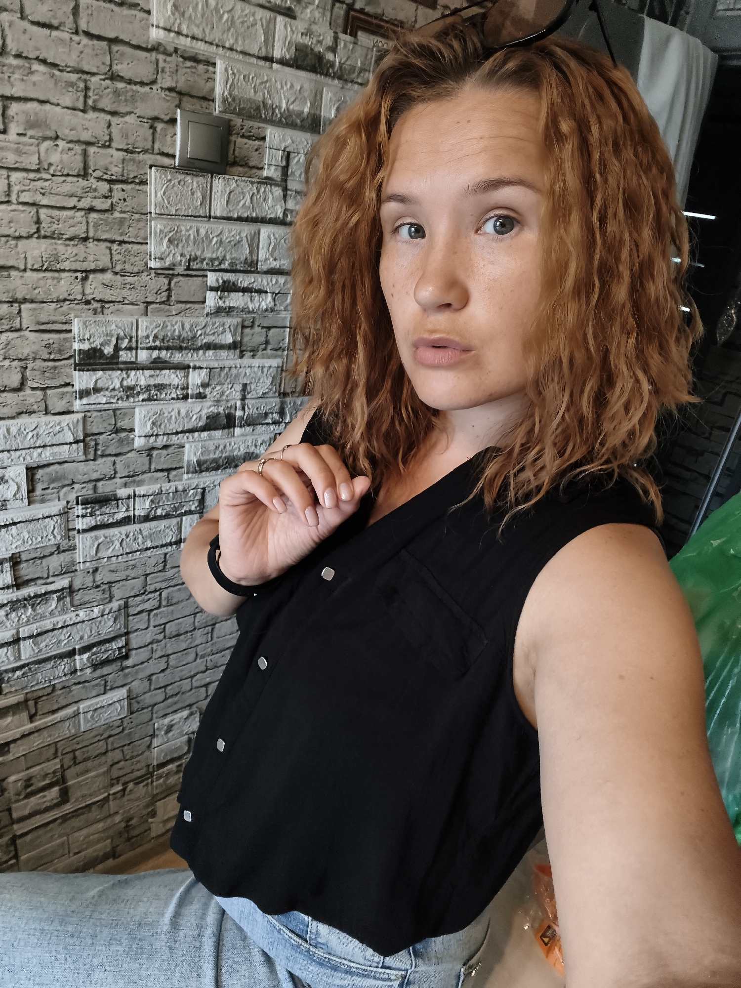 Indoor selfie against a grey brick-patterned wall.