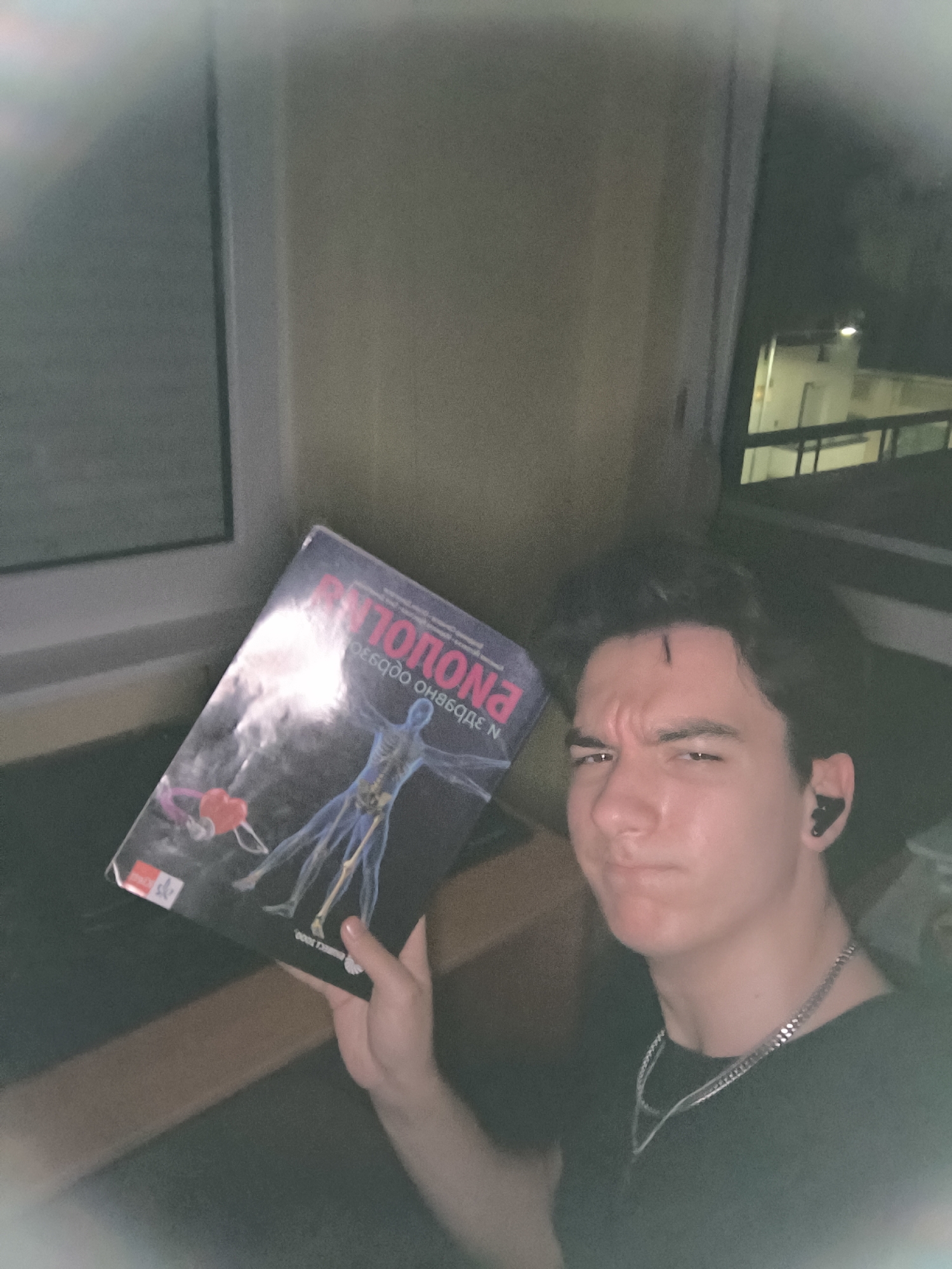 Young man reading encyclopedia, resting in Pleven apartment evening