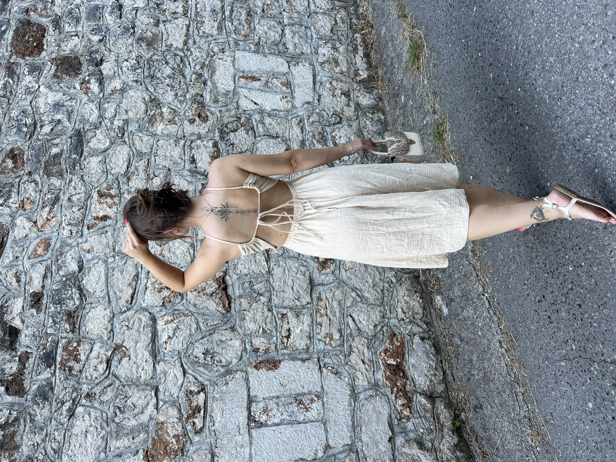 Woman in beige dress walks along stone-walled road in Podgorica