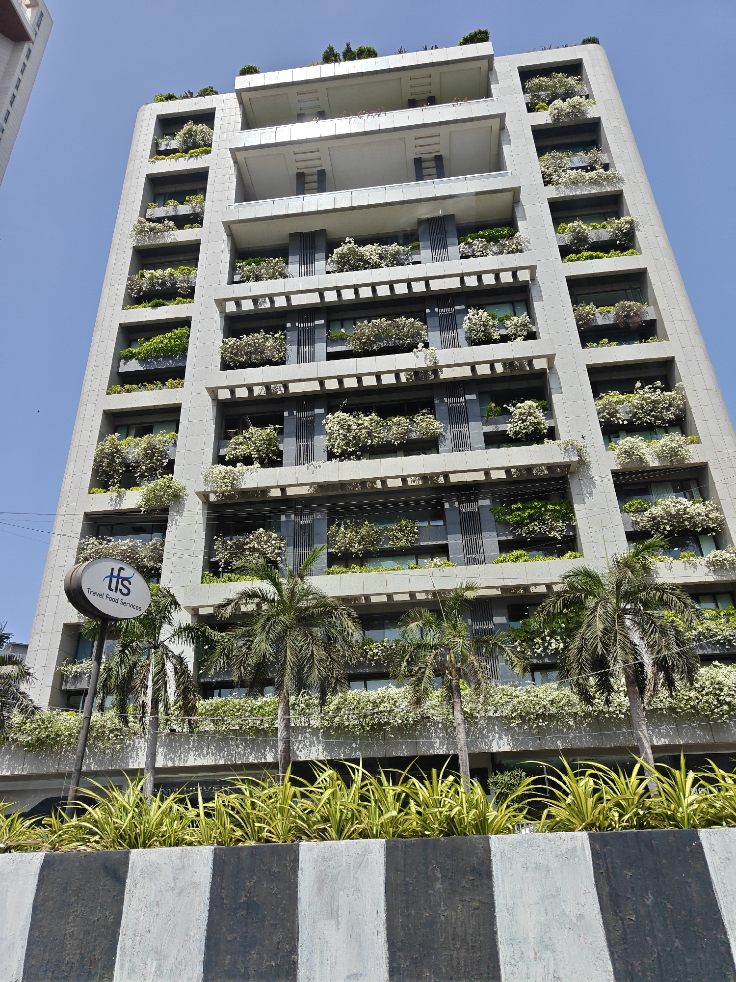 Modern Mumbai building displays extensive balcony gardens, flowering plants