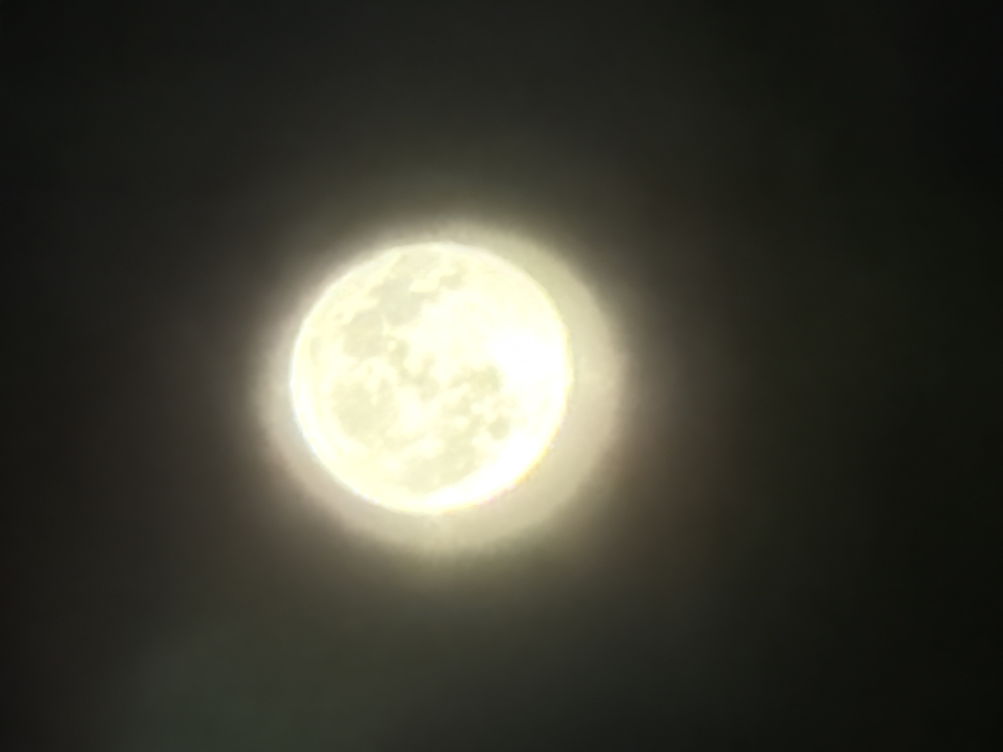 Full moon glows through thin clouds over a Russian village