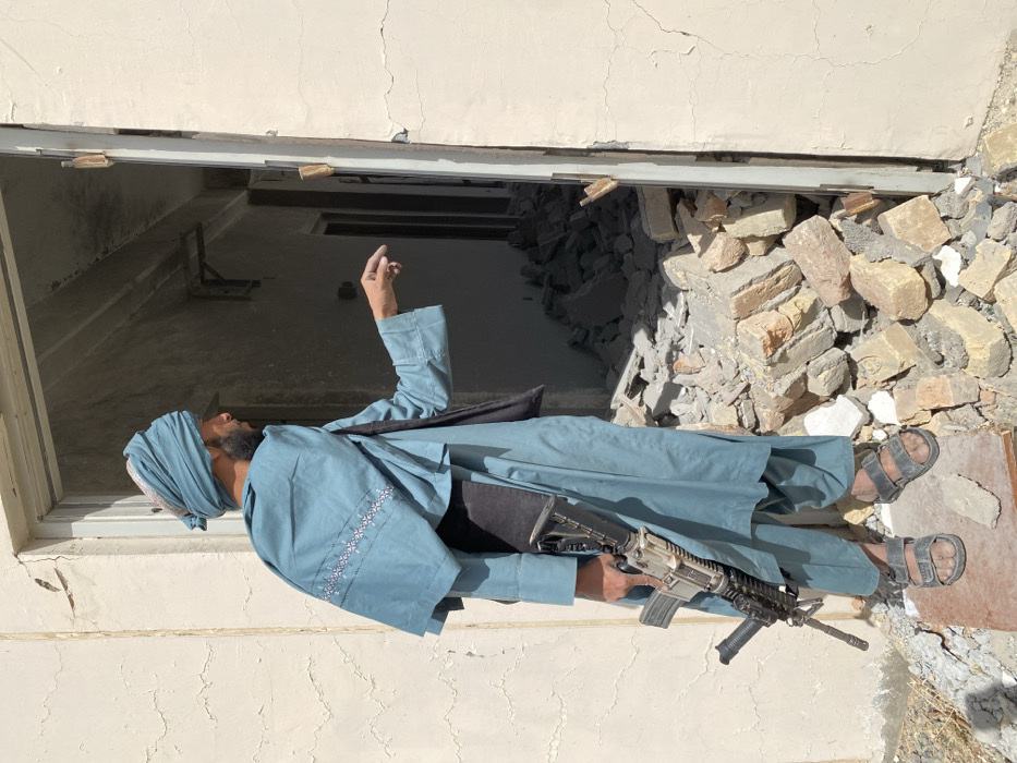 Armed men survey heavily damaged building in Mandisar, Afghanistan