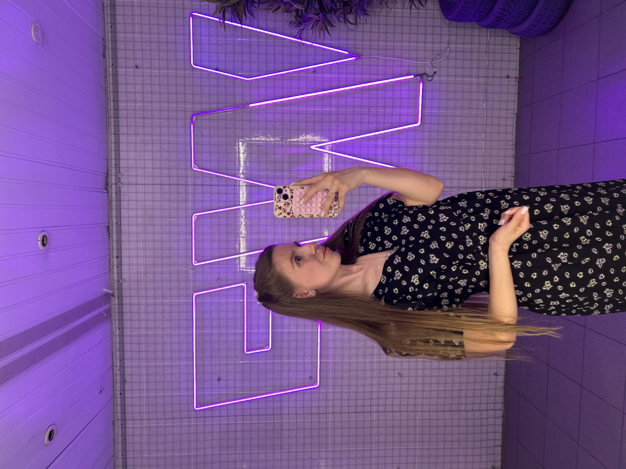 Woman takes selfies in neon-lit venue in Klin, Russia