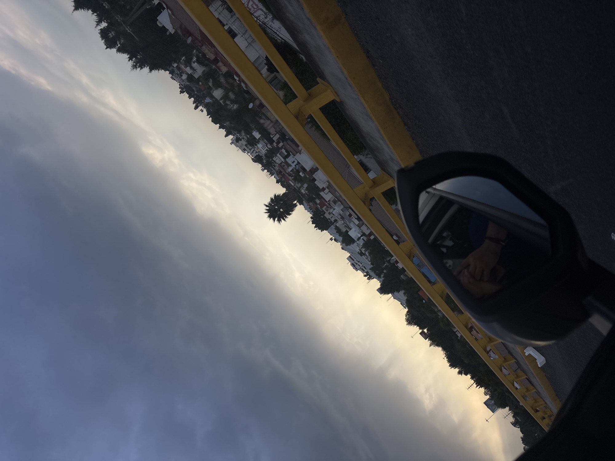 Nighttime vehicle travel captured through side mirror in Cholula
