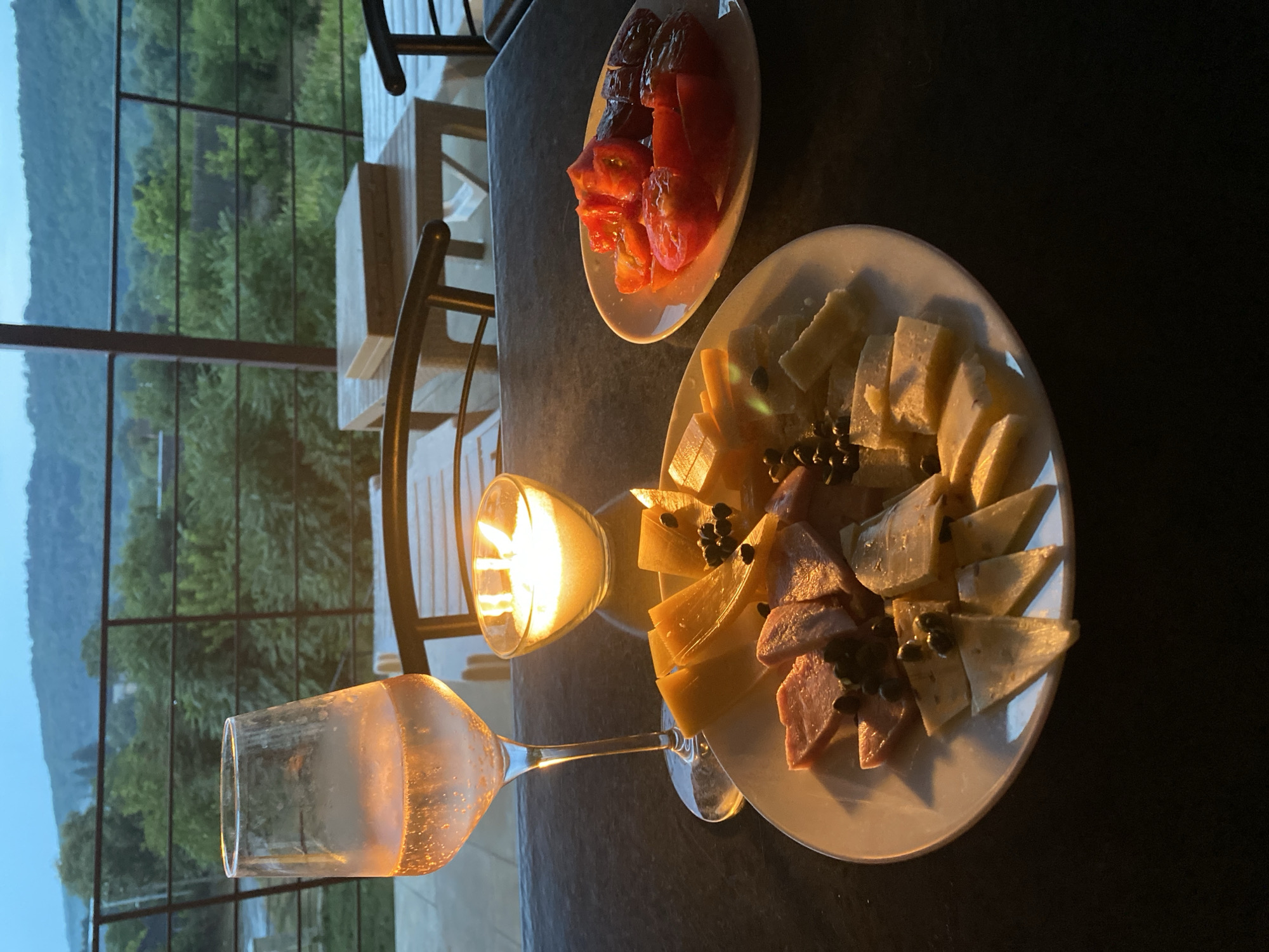 Sparkling drink on a balcony overlooking Busha's green hills at dusk