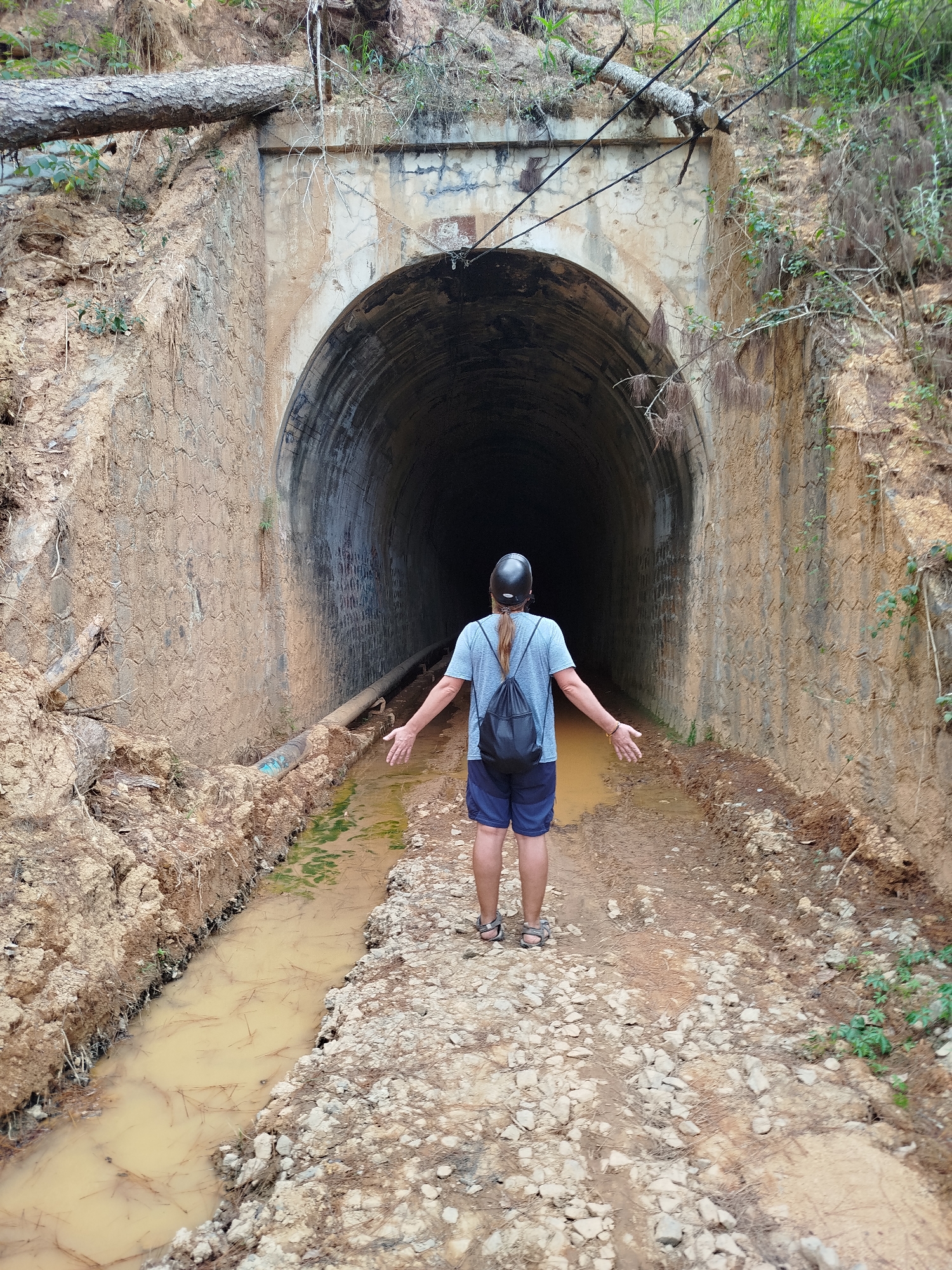 Person explores muddy tunnel system in Vietnamese forest