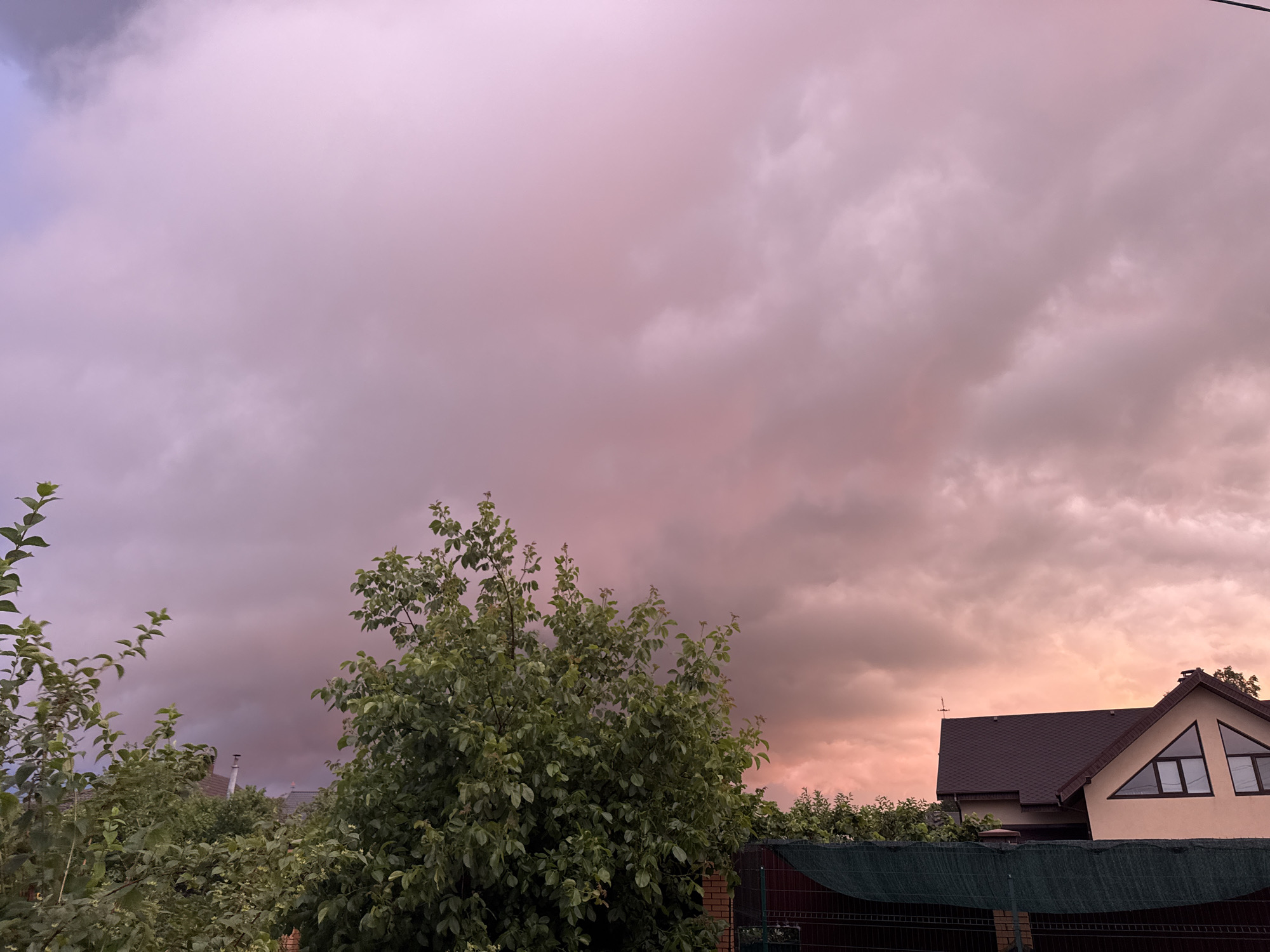 Dramatic storm clouds roll over a residential neighborhood at golden hour.