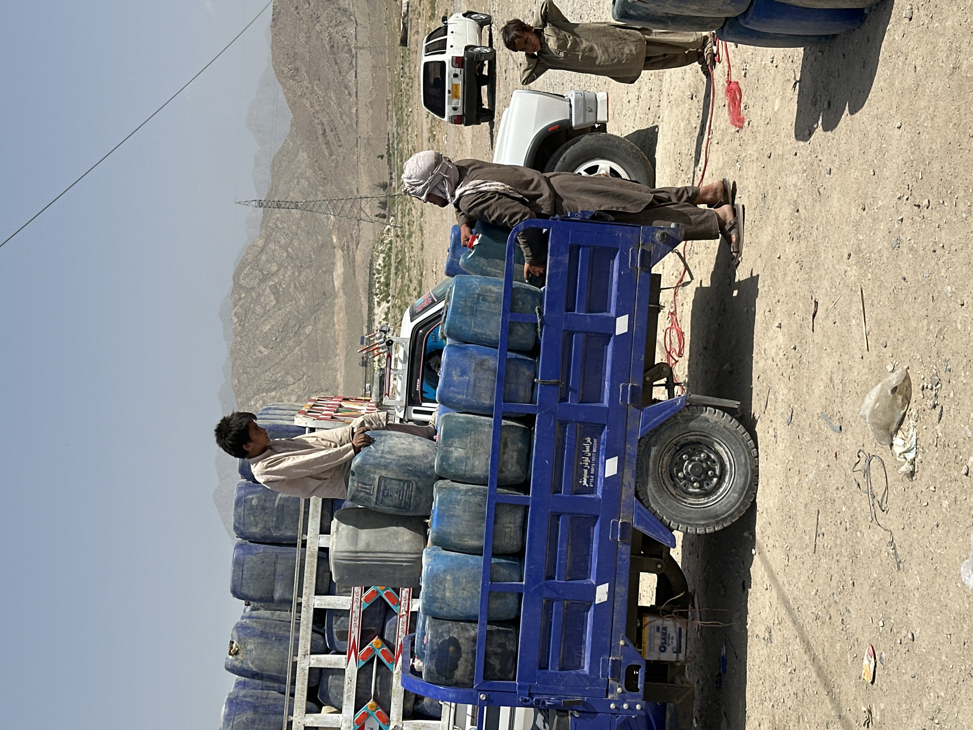 Blue truck convoy transports containers in Pakistan mountains